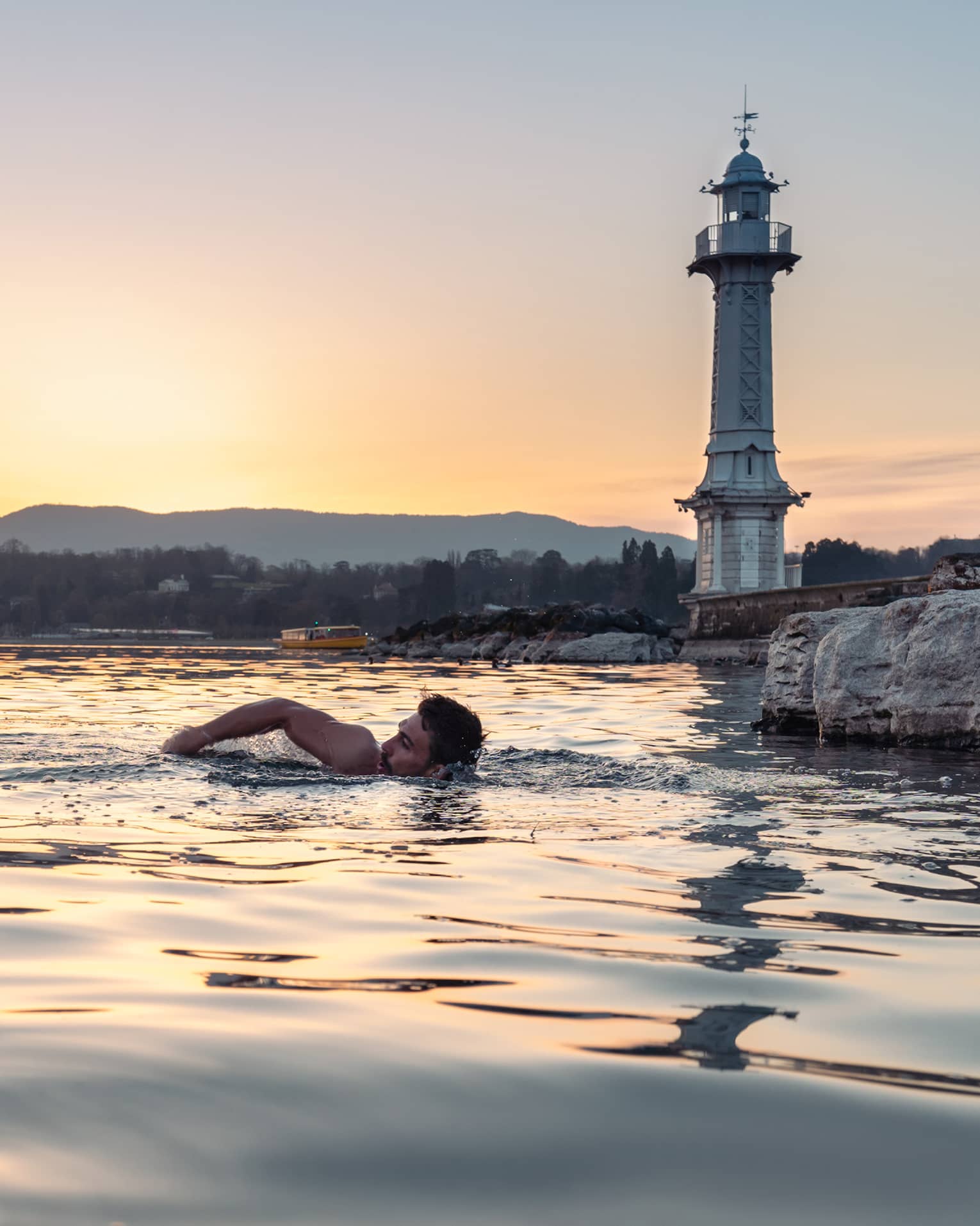 Person swimming in Lake Geneva at sunset