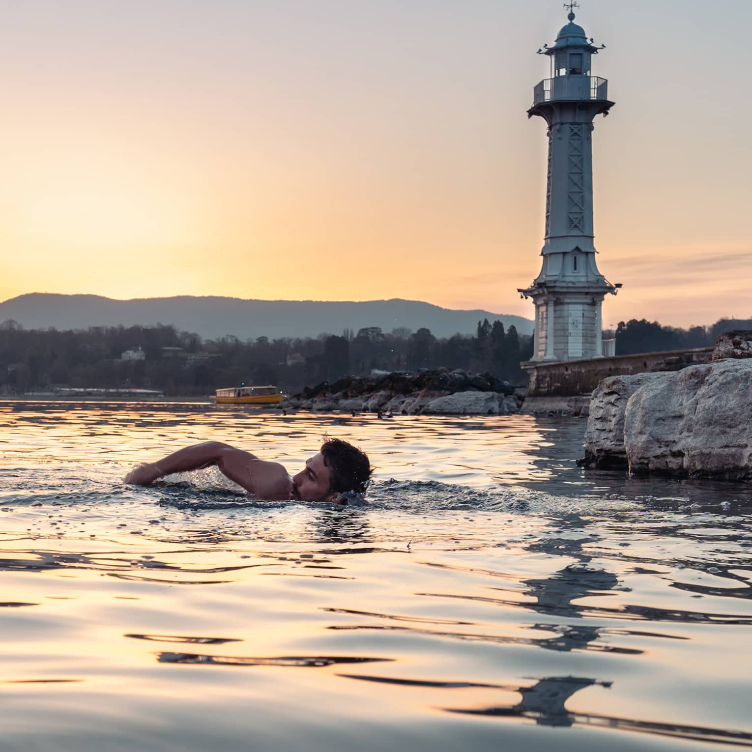Person swimming in Lake Geneva at sunset