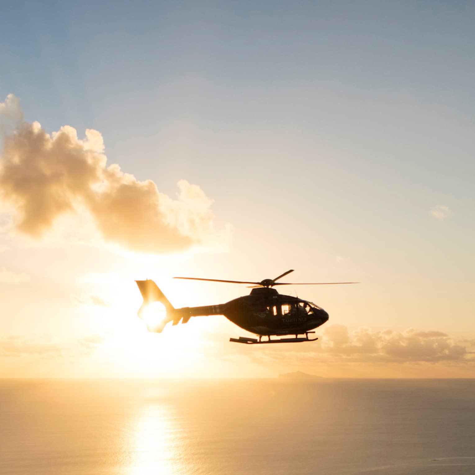 Helicopter over the sea at sunset