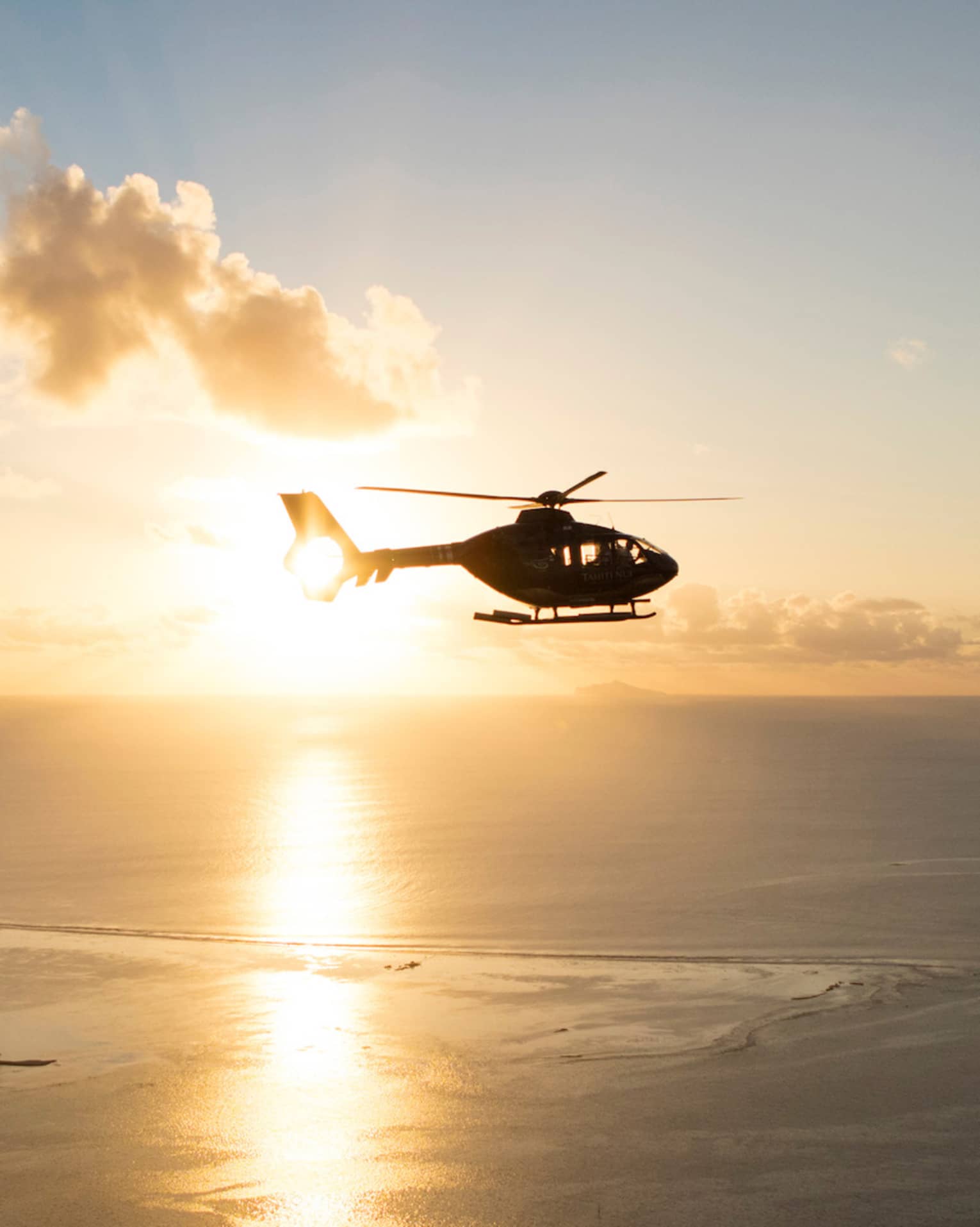 Helicopter over the sea at sunset