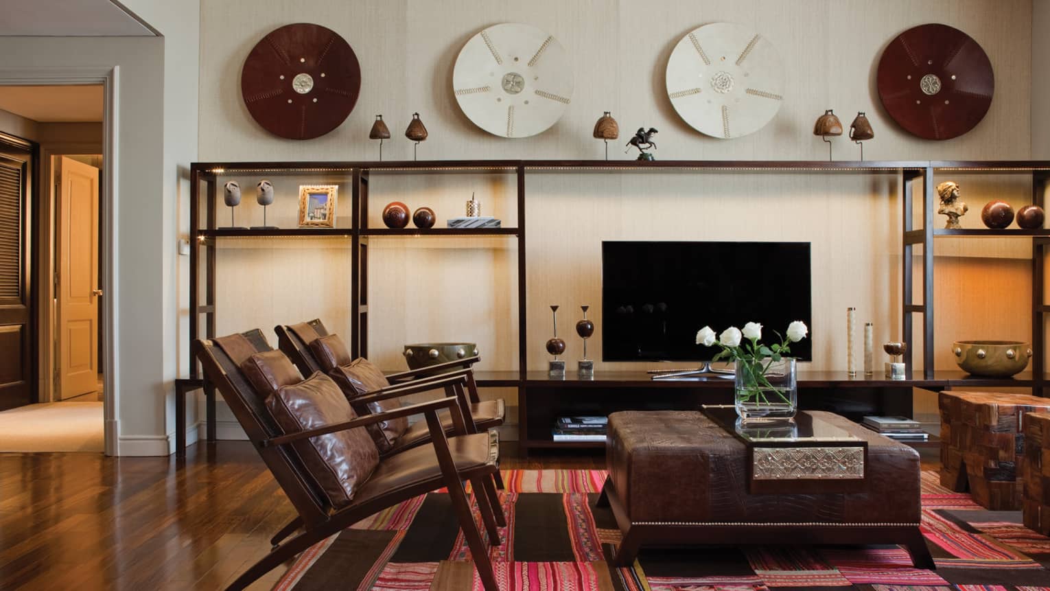 Modern brown leather armchairs and large ottoman with fresh flowers, modern and wood Argentine-inspired art