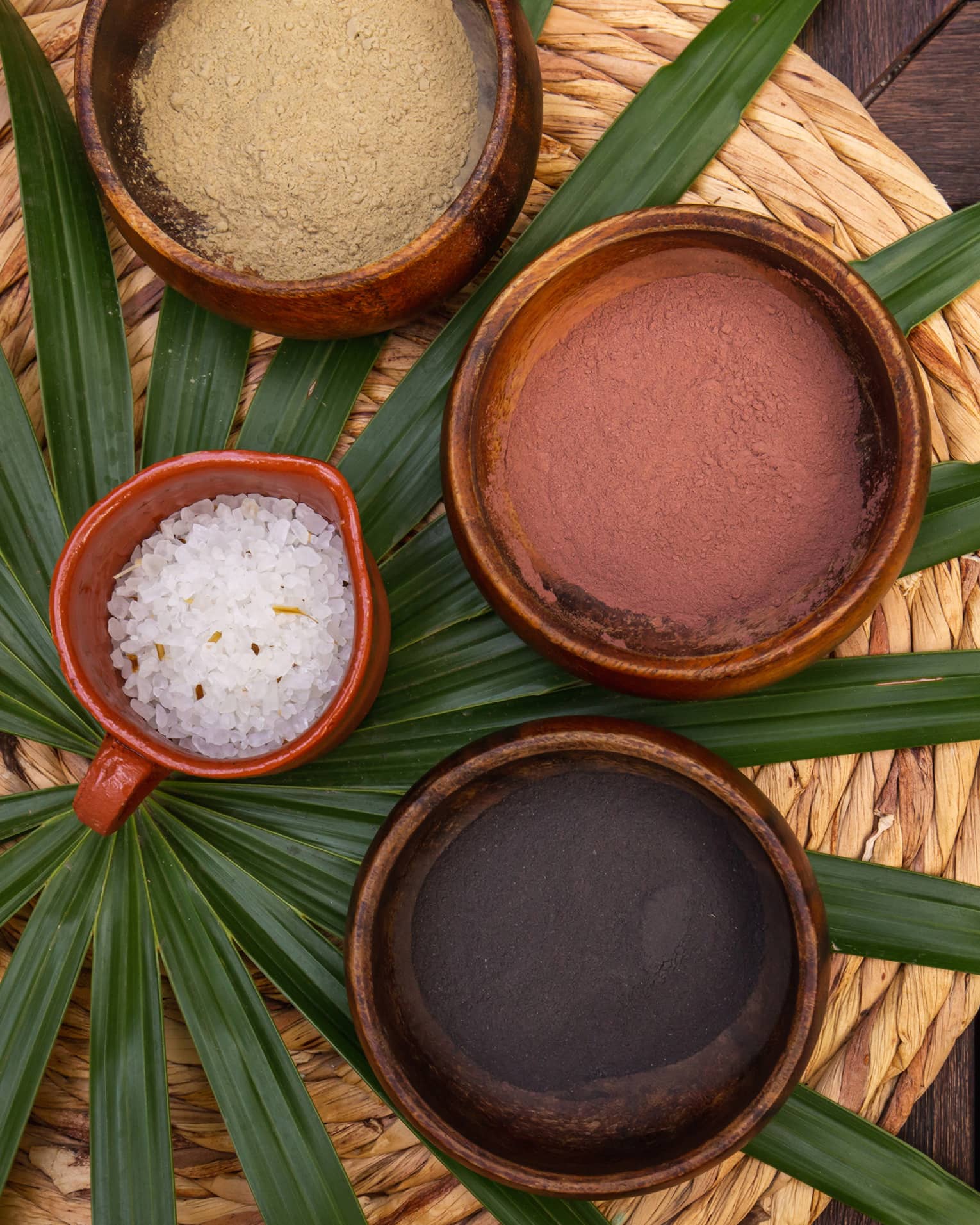 Various spa minerals in bowls on a large leaf.