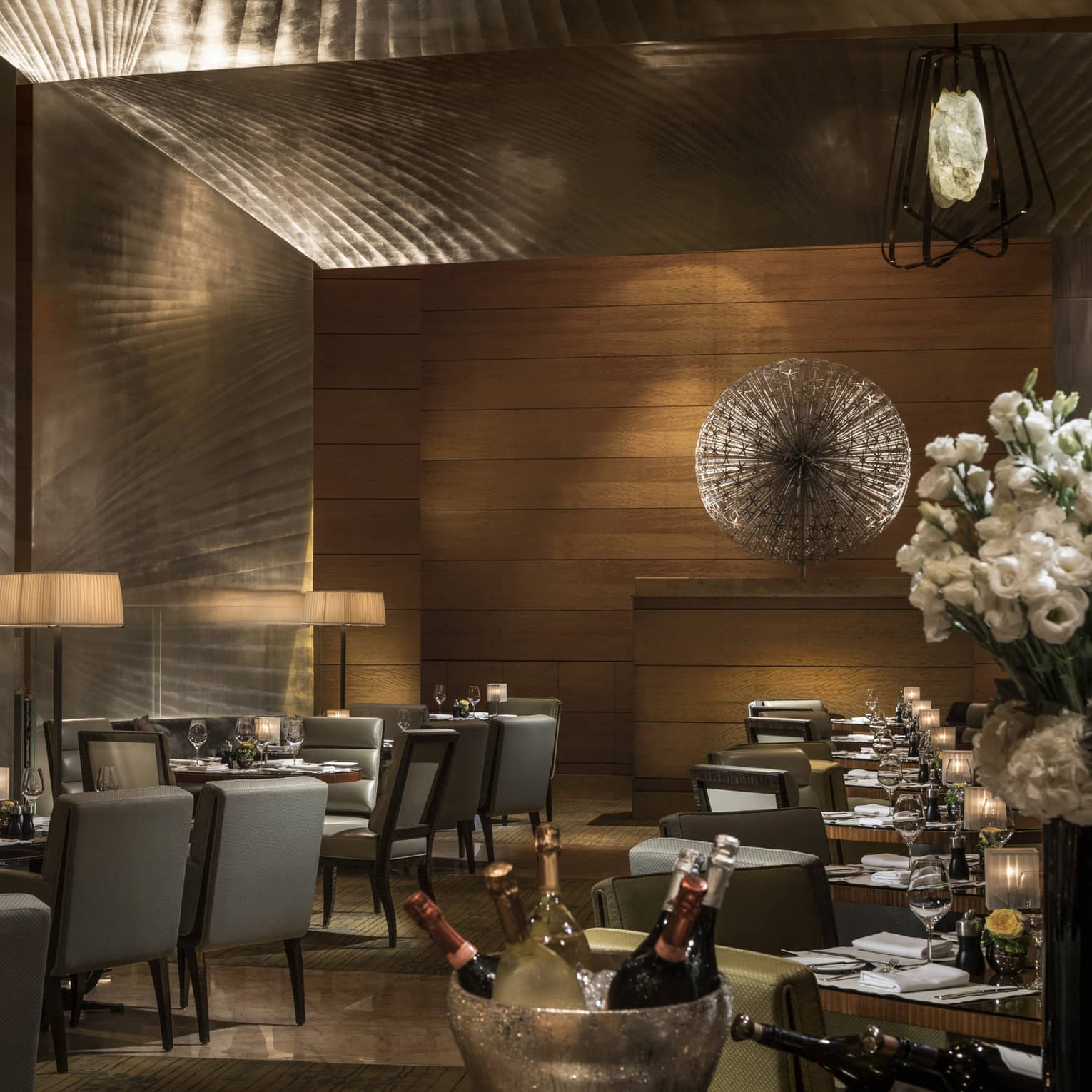 Elegant restaurant dining area with softly lit tables, upholstered chairs, and ambient lighting, set for a formal dinner service.