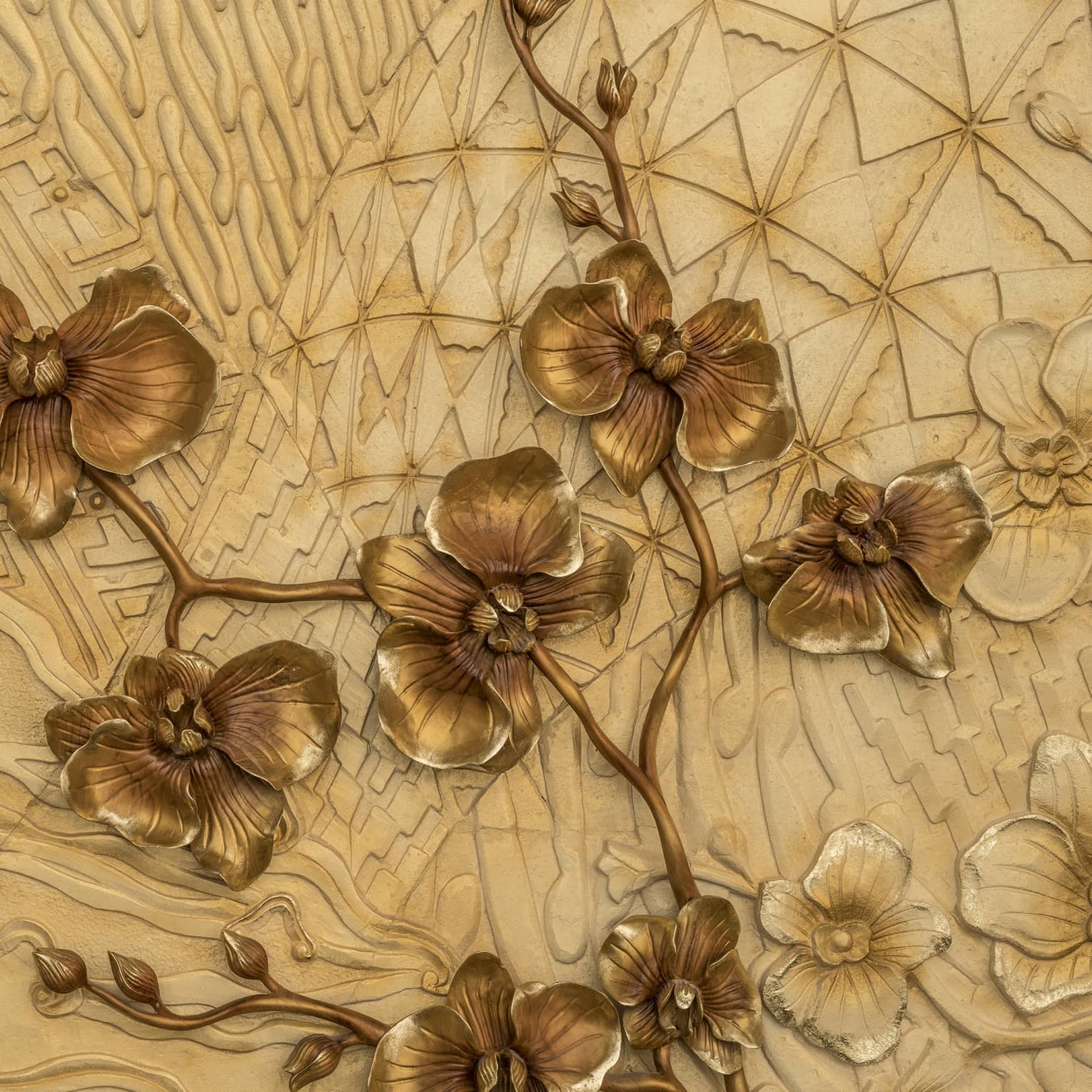 Close-up of batik design with metal bronze-coloured flowers sprouting across a tan background of varying bas-relief patterns.