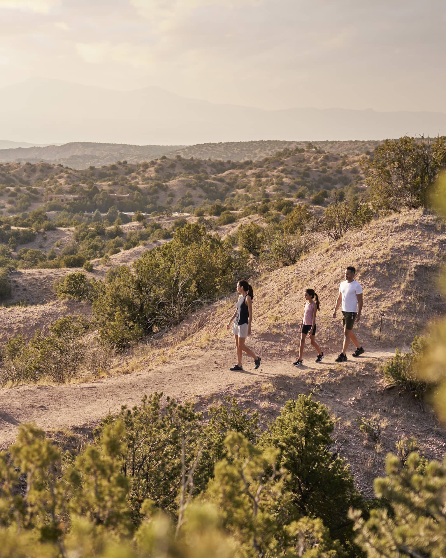 A family of three hiking over sand.