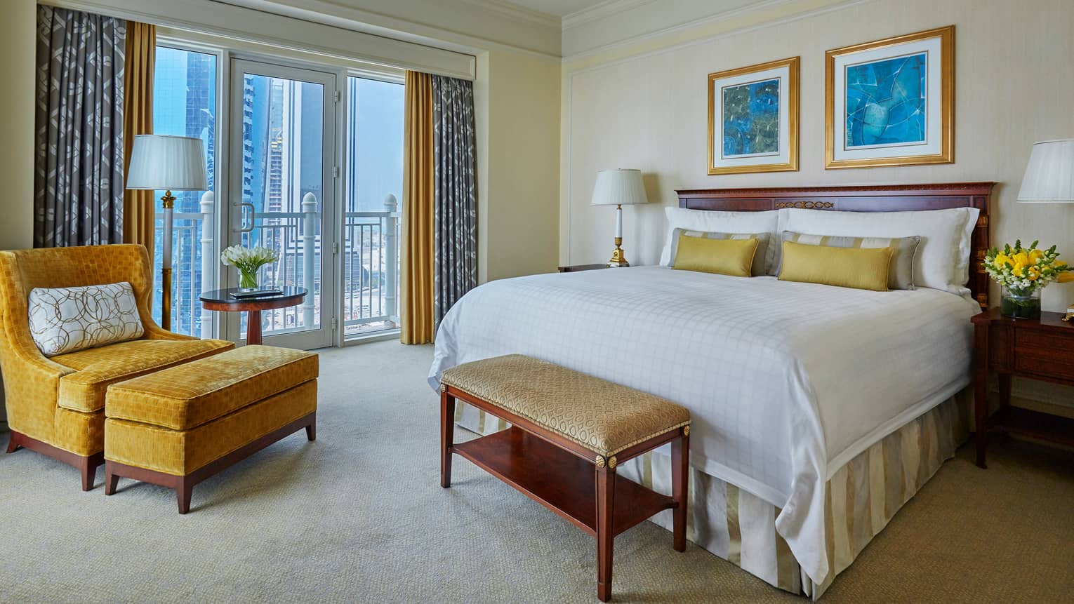 West Bay Three-Bedroom Suite bed with white linens, accent pillows, gold velvet chair by window