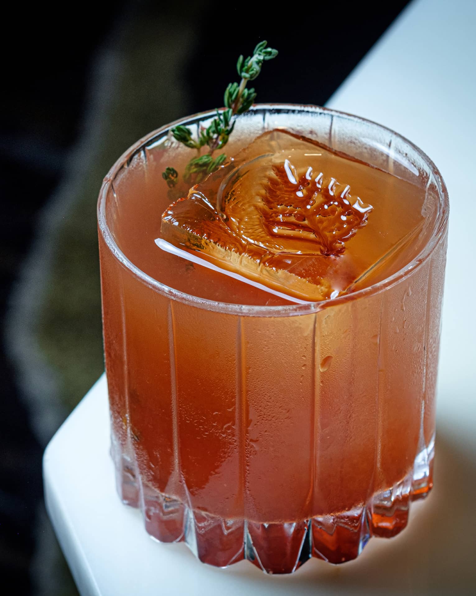 An amber coloured cocktail with a leaf imprinted into the ice.