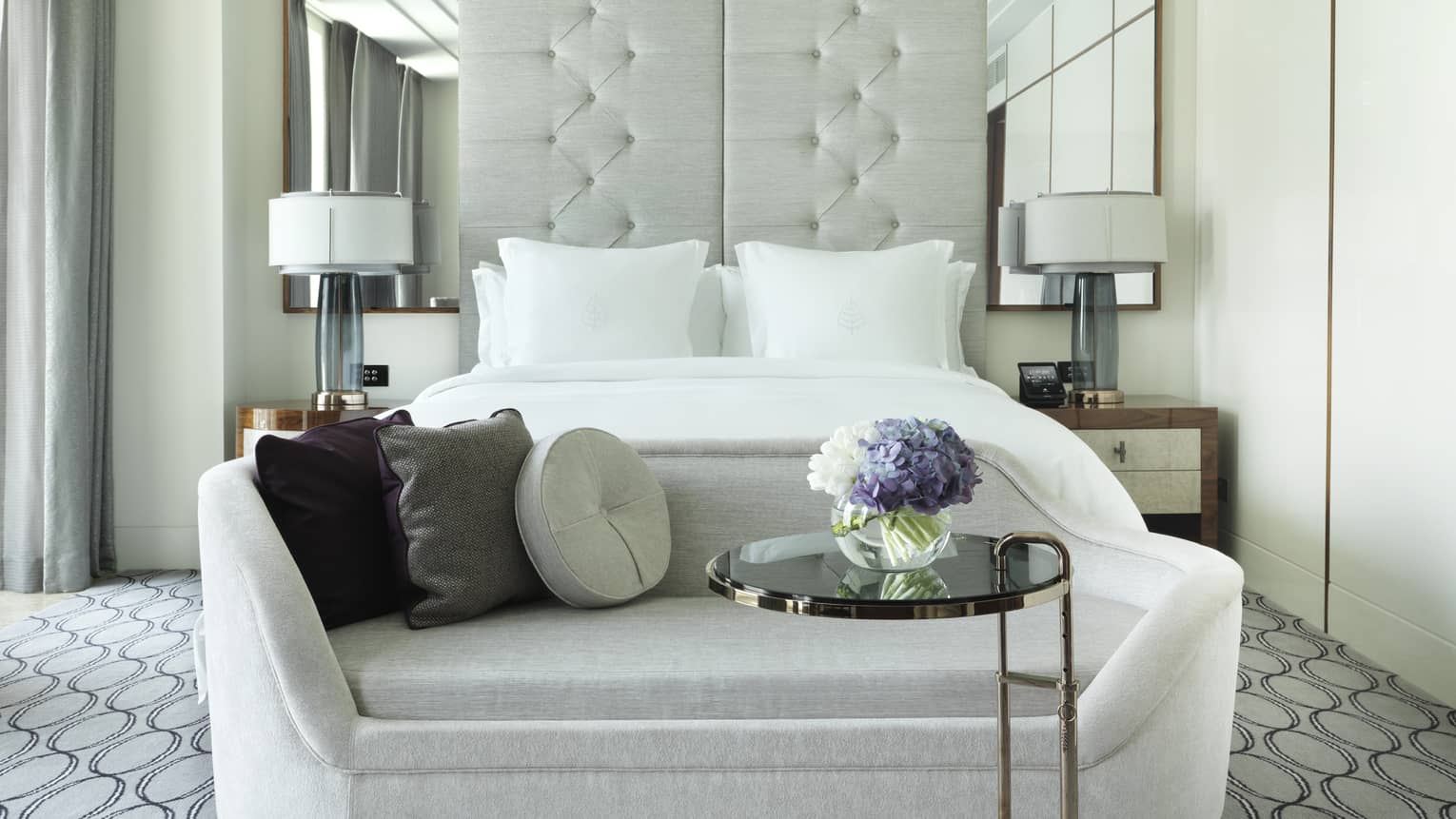Front view of plush white sofa with small brass table at front of bed in Deluxe Room