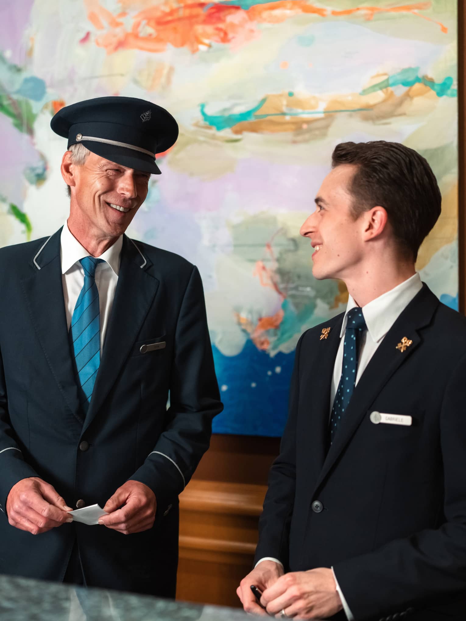 Two people in suits stand behind hotel welcome reception counter