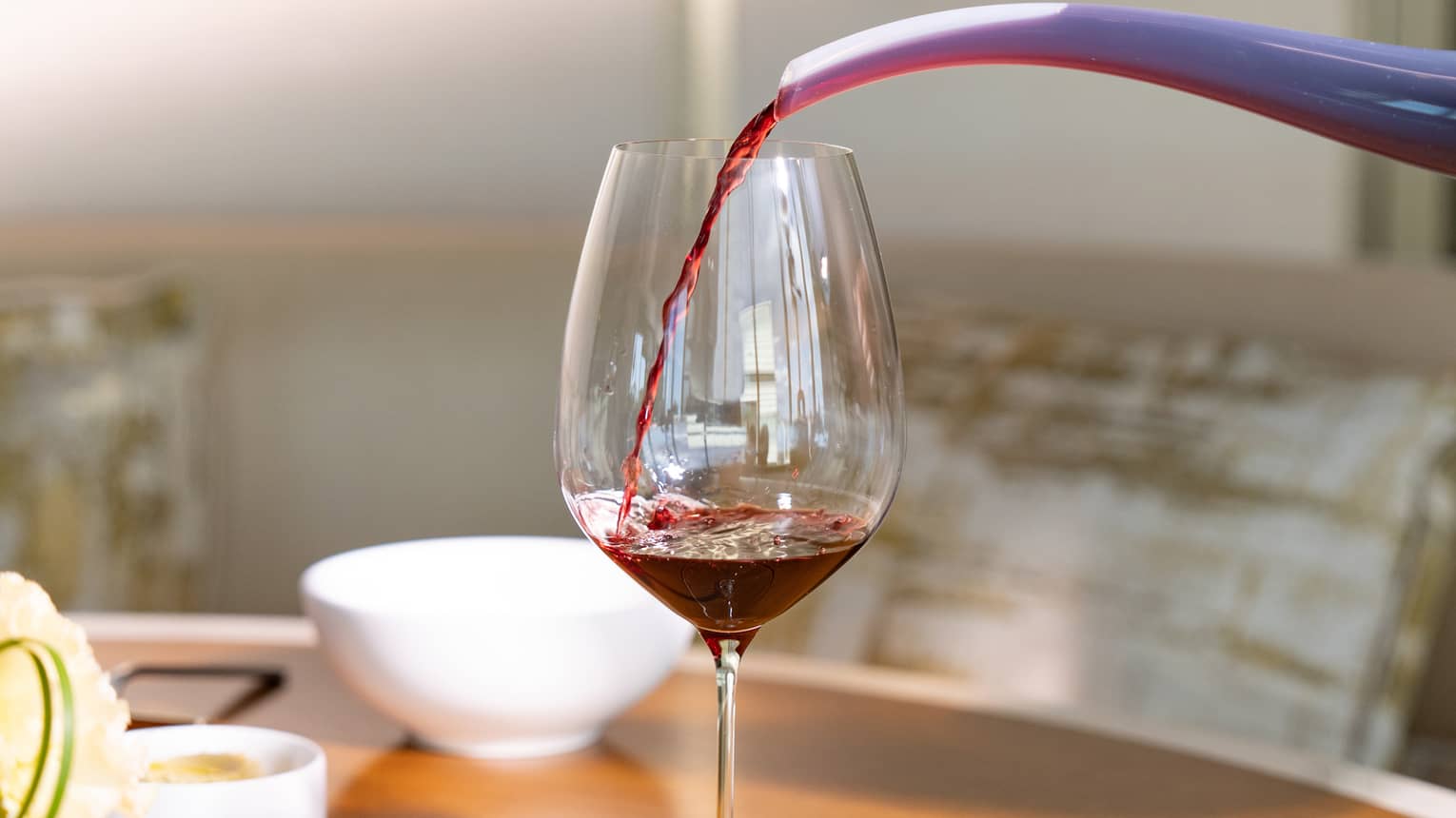 Red wine is poured into a glass from a decanter