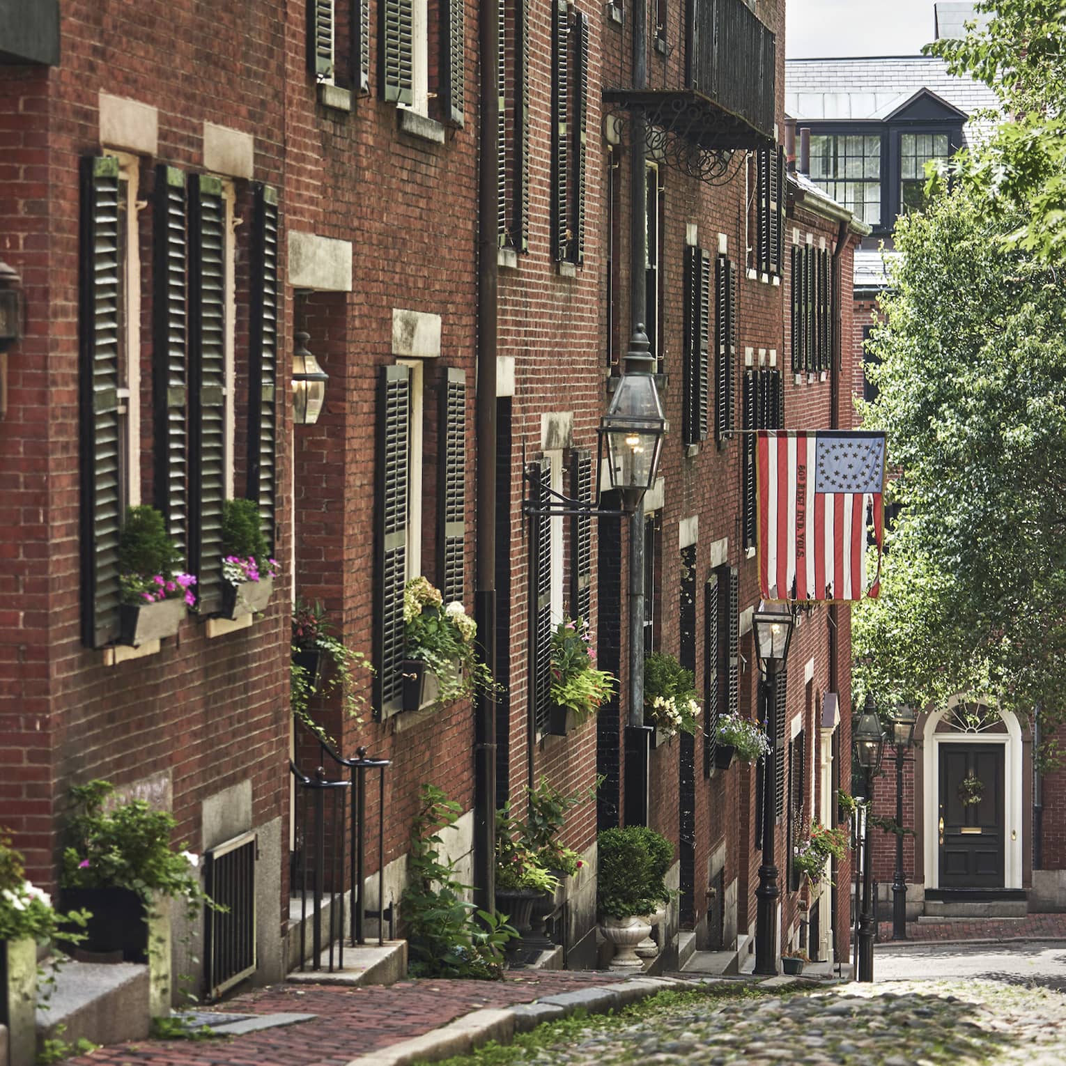 A cobblestone alley in Beacon Hill, lined with red brick residential buildings 