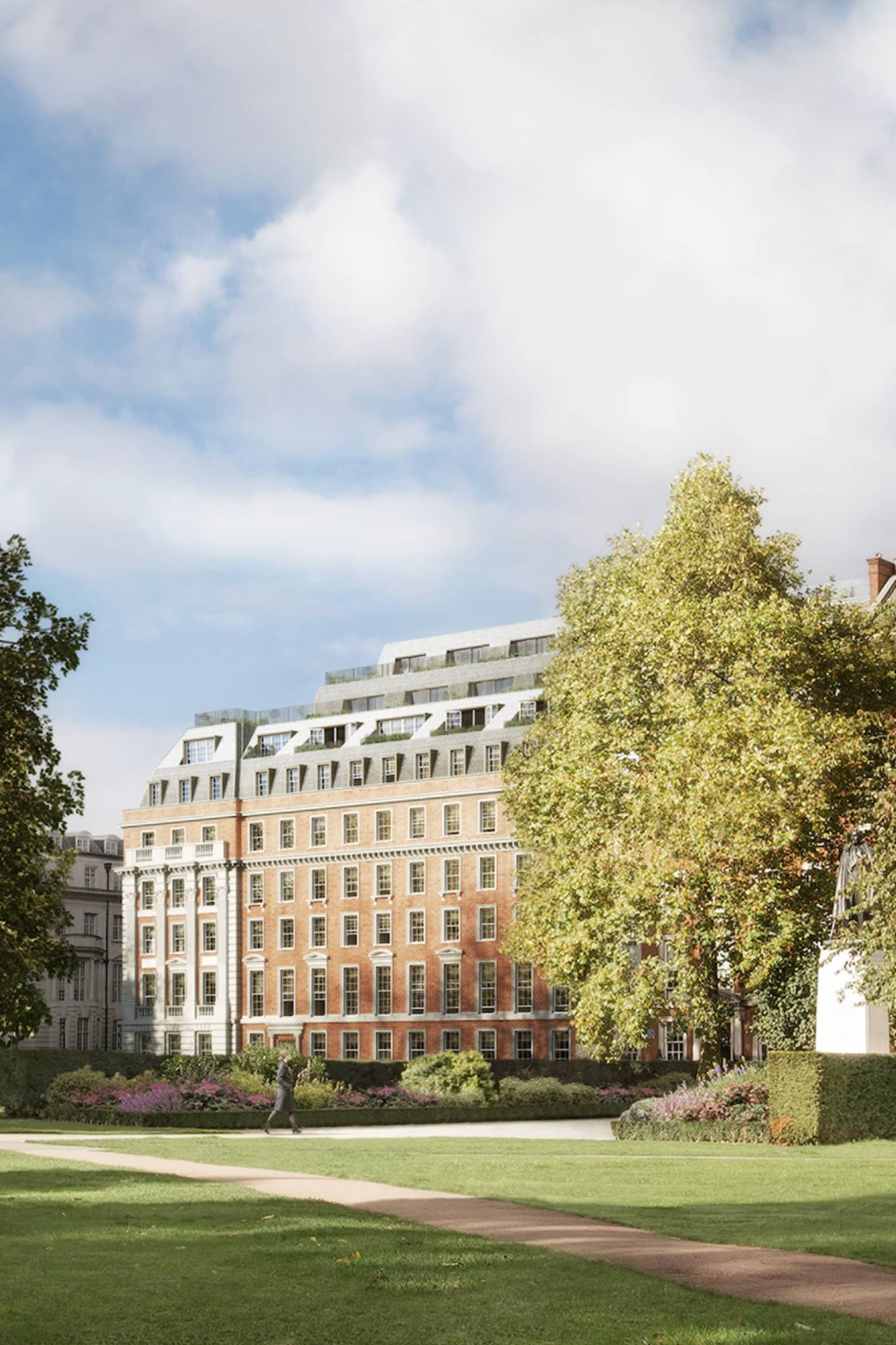 View across long green park, path between trees to building in background