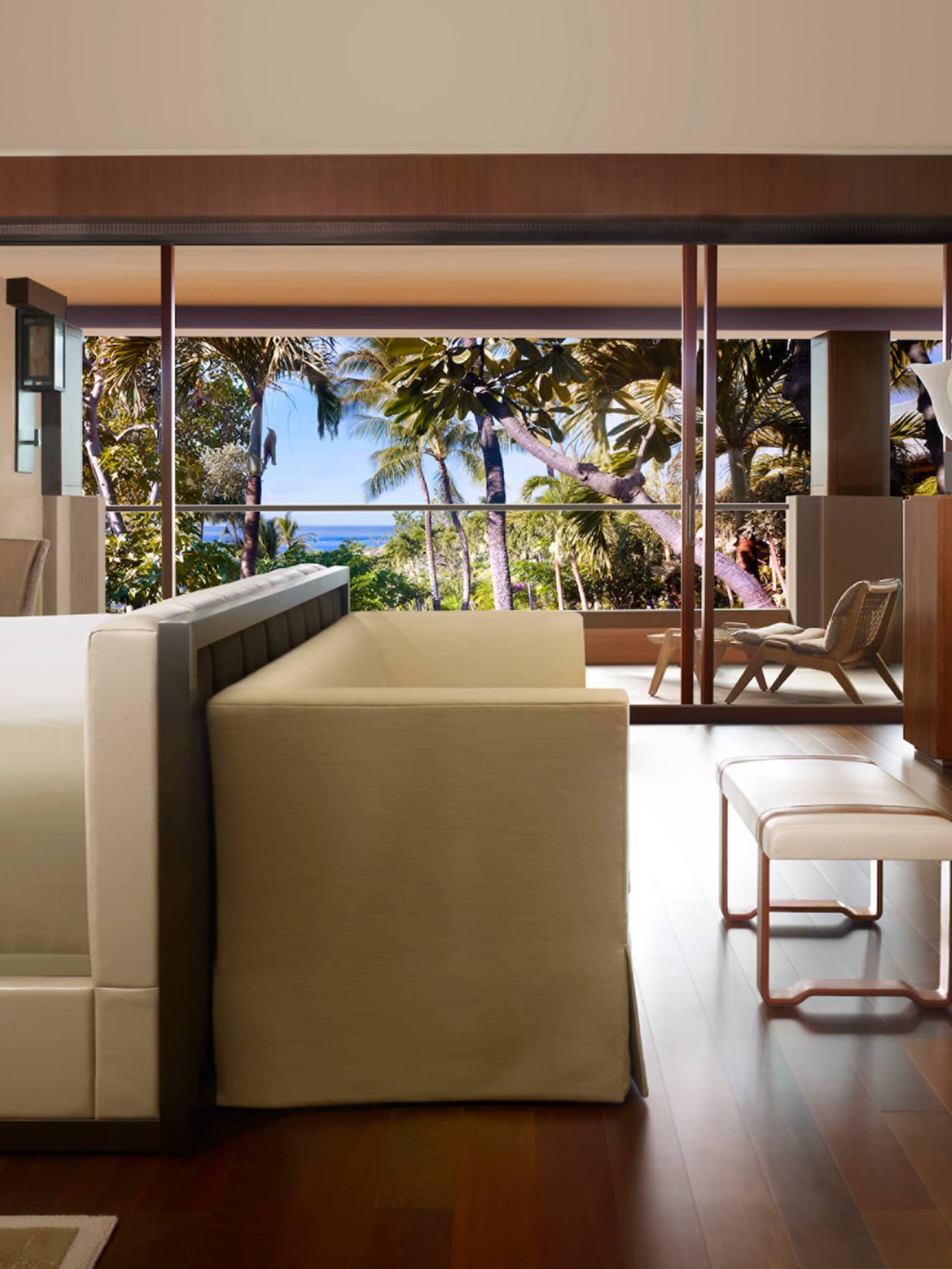 Ohana Partial Ocean-View Suite side view of bed with small white sofa, bench at foot, wood floors