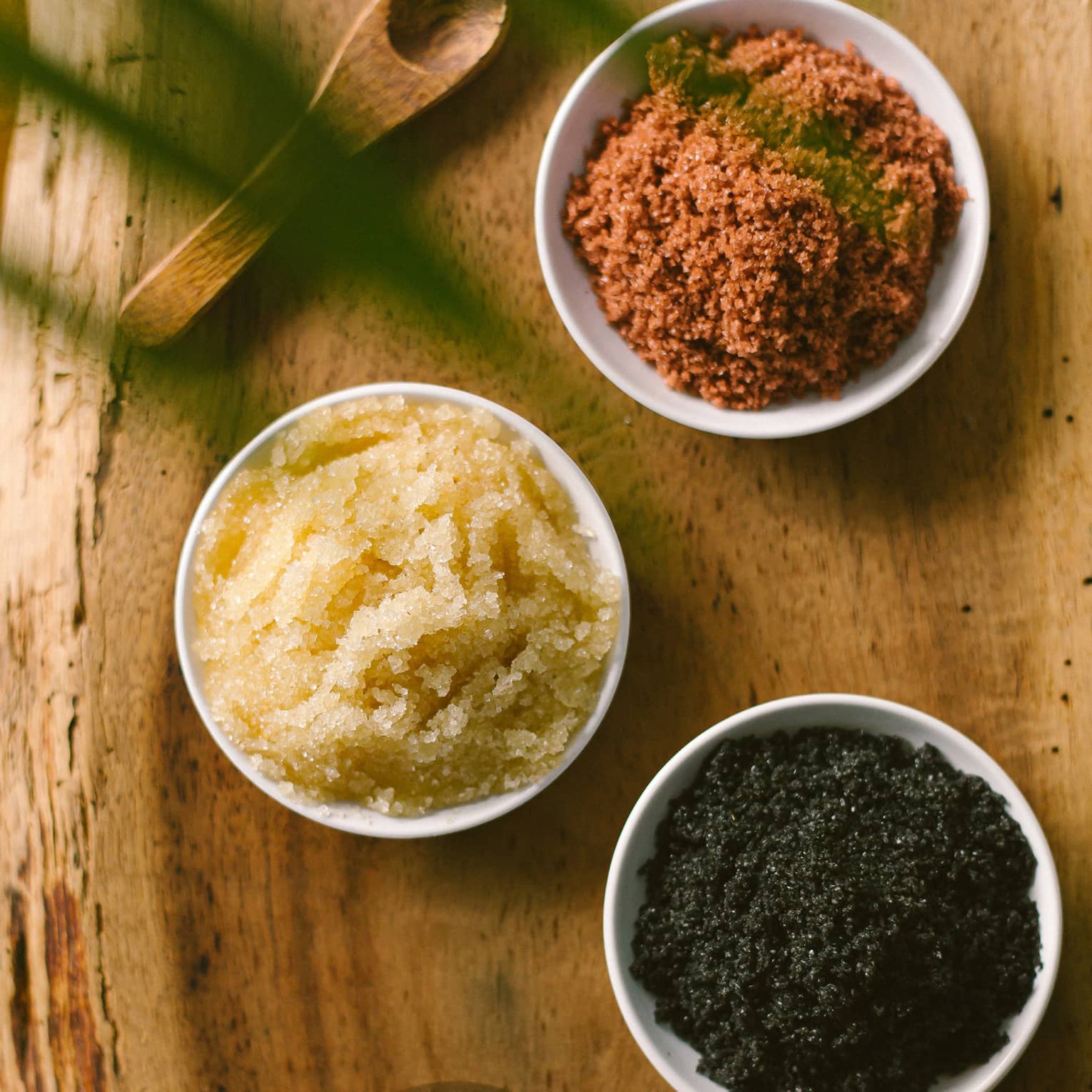Aerial view of three dishes with salt scrubs on rustic wood platter