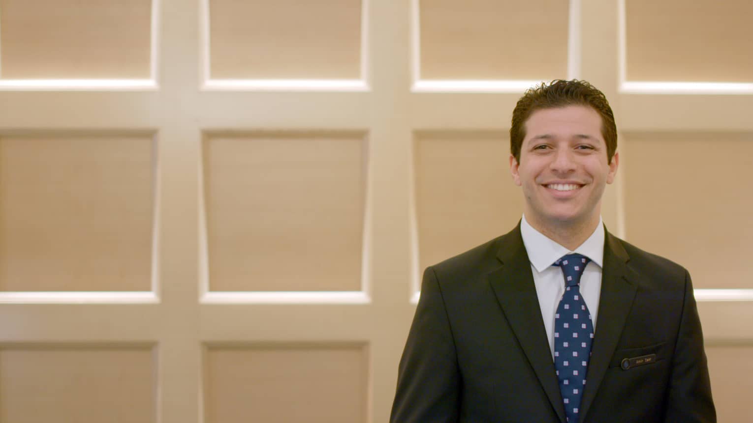 Man behind a reception desk in a suit and tie
