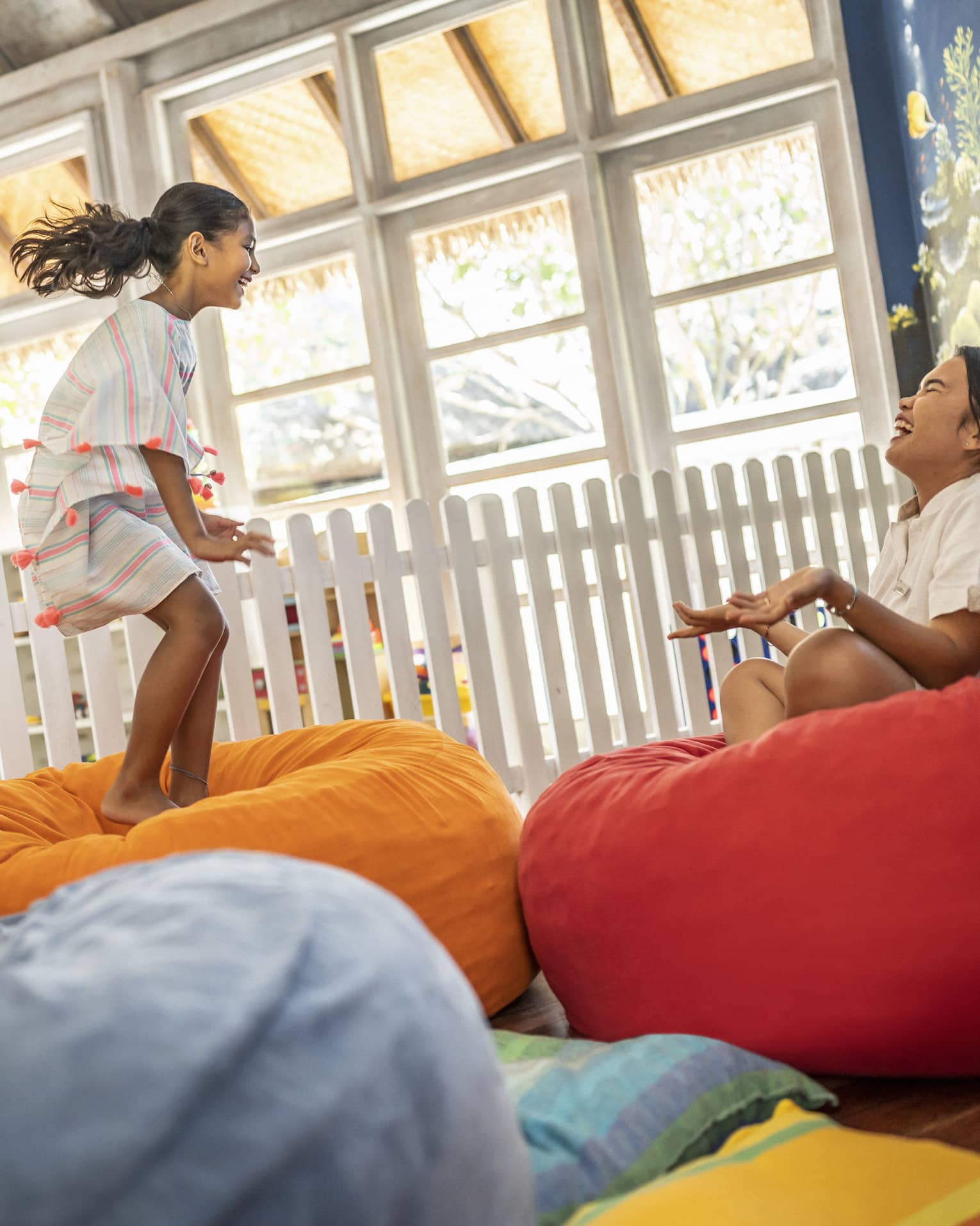 Young girl jumps on bean bag with dedicated attendant in the Kids Club