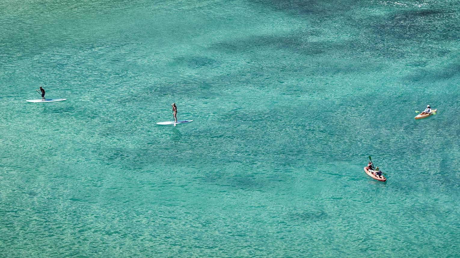 Aerial view of stand-up paddleboarders, boats on lagoon