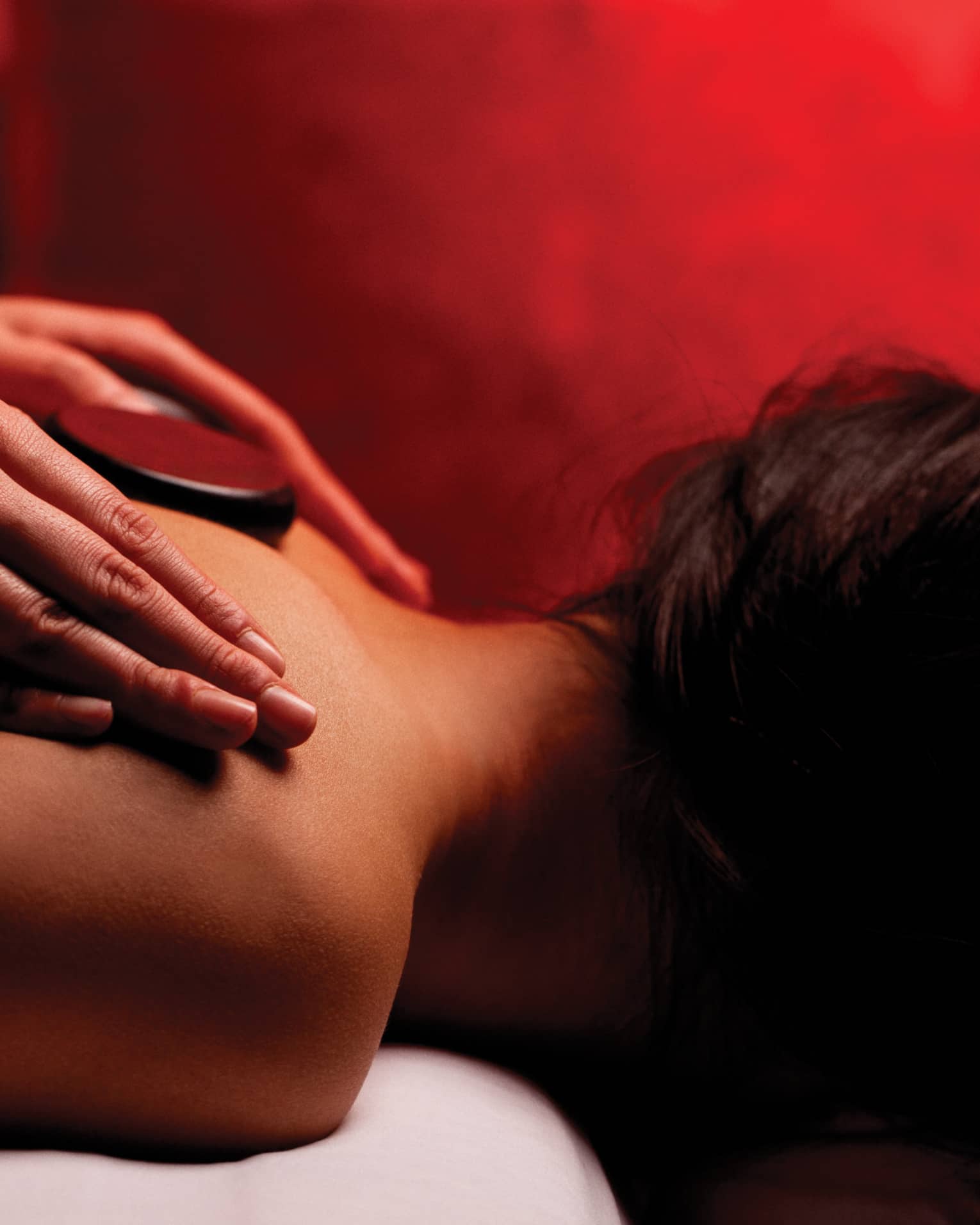 Hands rub woman's bare shoulders during Fusion Massage in spa