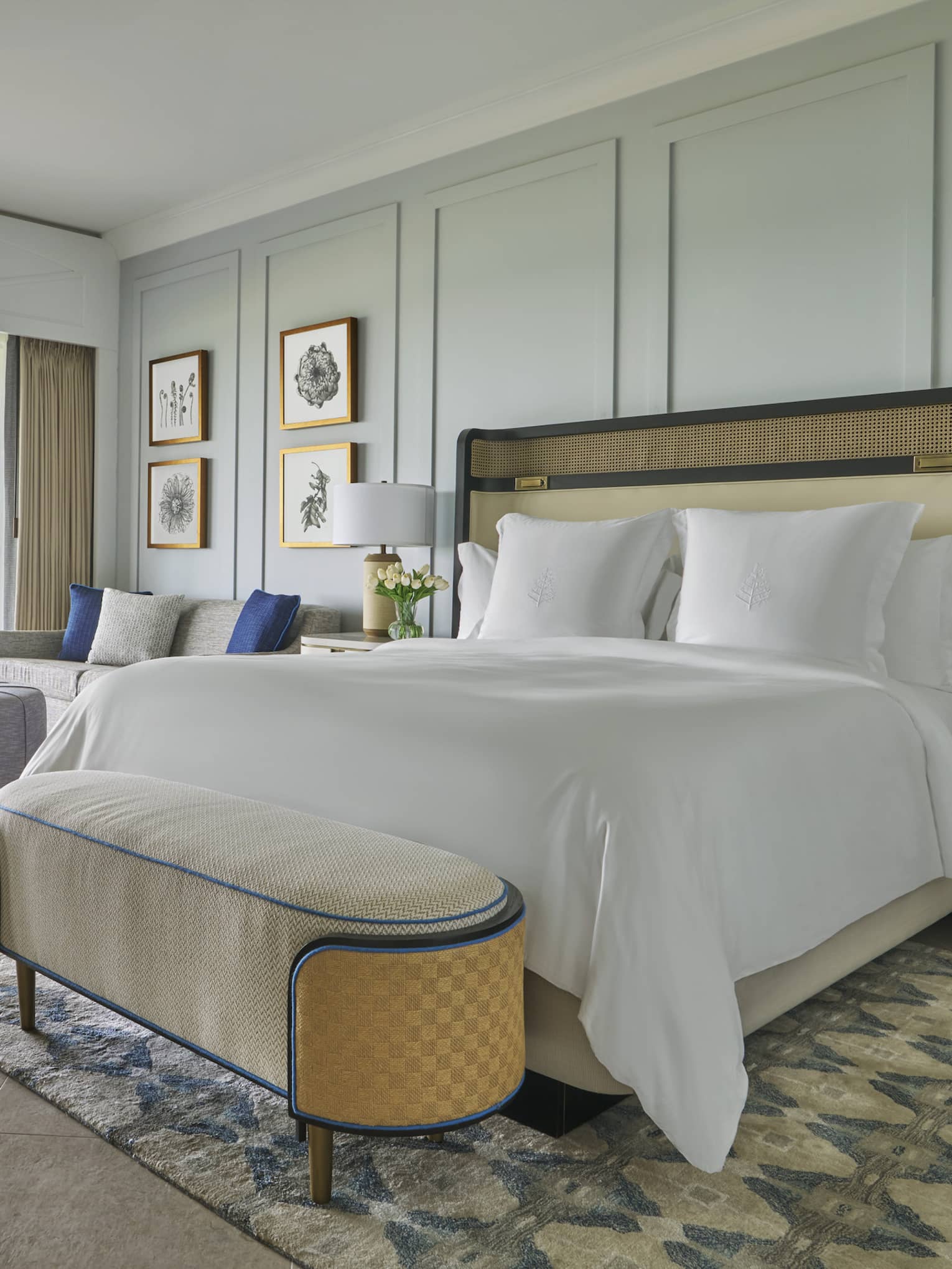 Luxury oceanfront bedroom with a large bed, cozy seating and sliding glass doors opening to a private patio with lounge chairs 