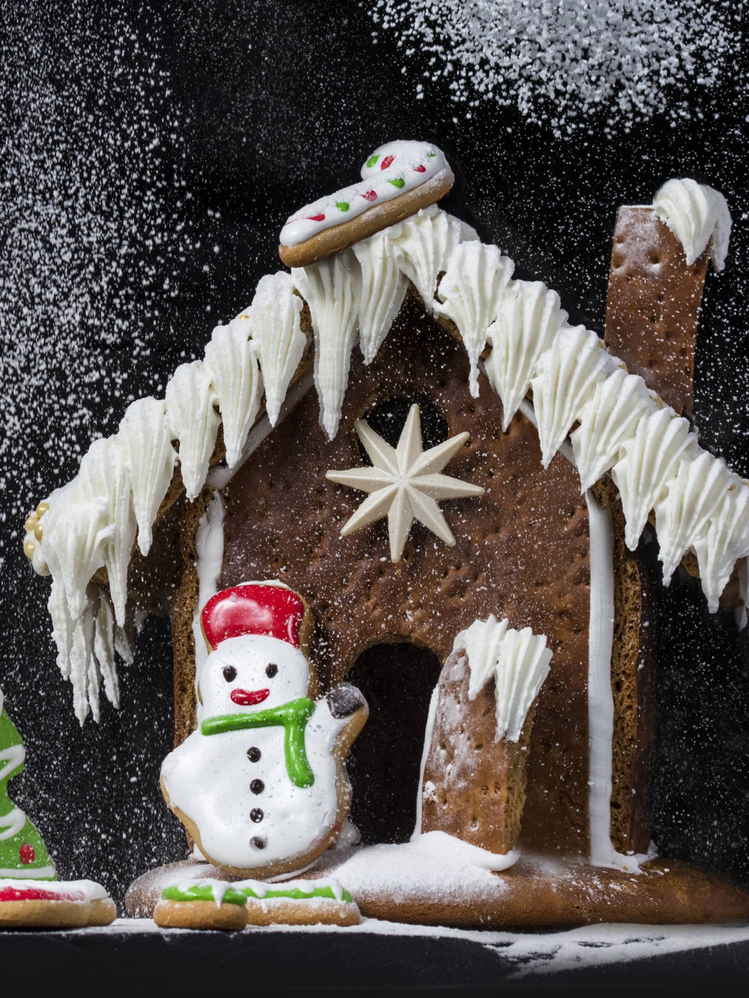 Gingerbread house being dusted with powdered sugar that looks like snow,Gingerbread house being dusted with powdered sugar that looks like snow