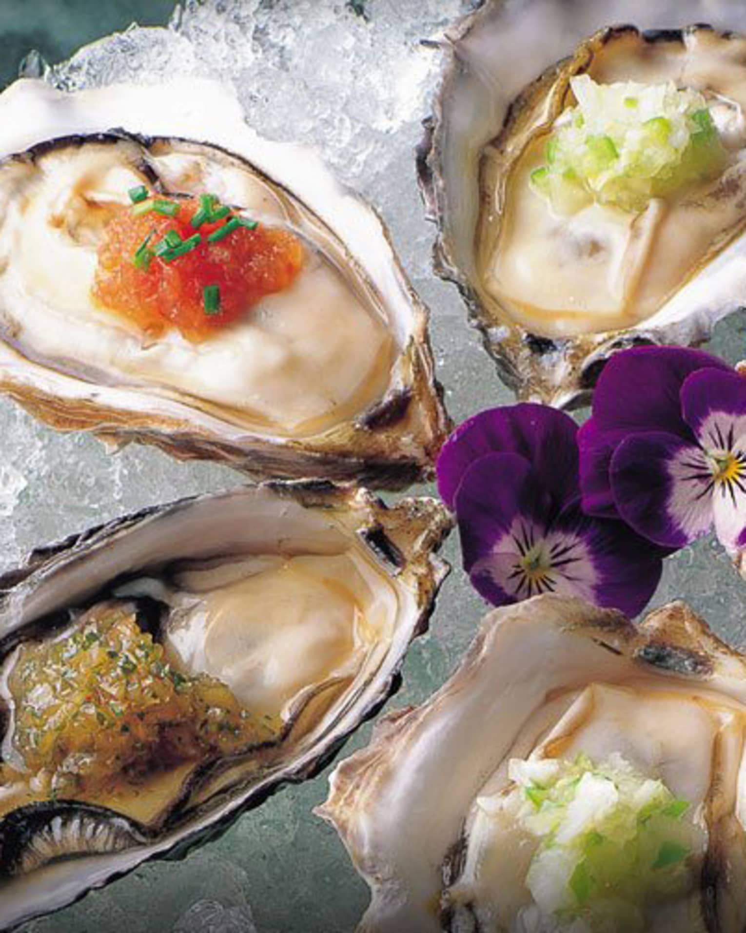 Raw oysters with Nobu Sauces and purple flowers on ice platter