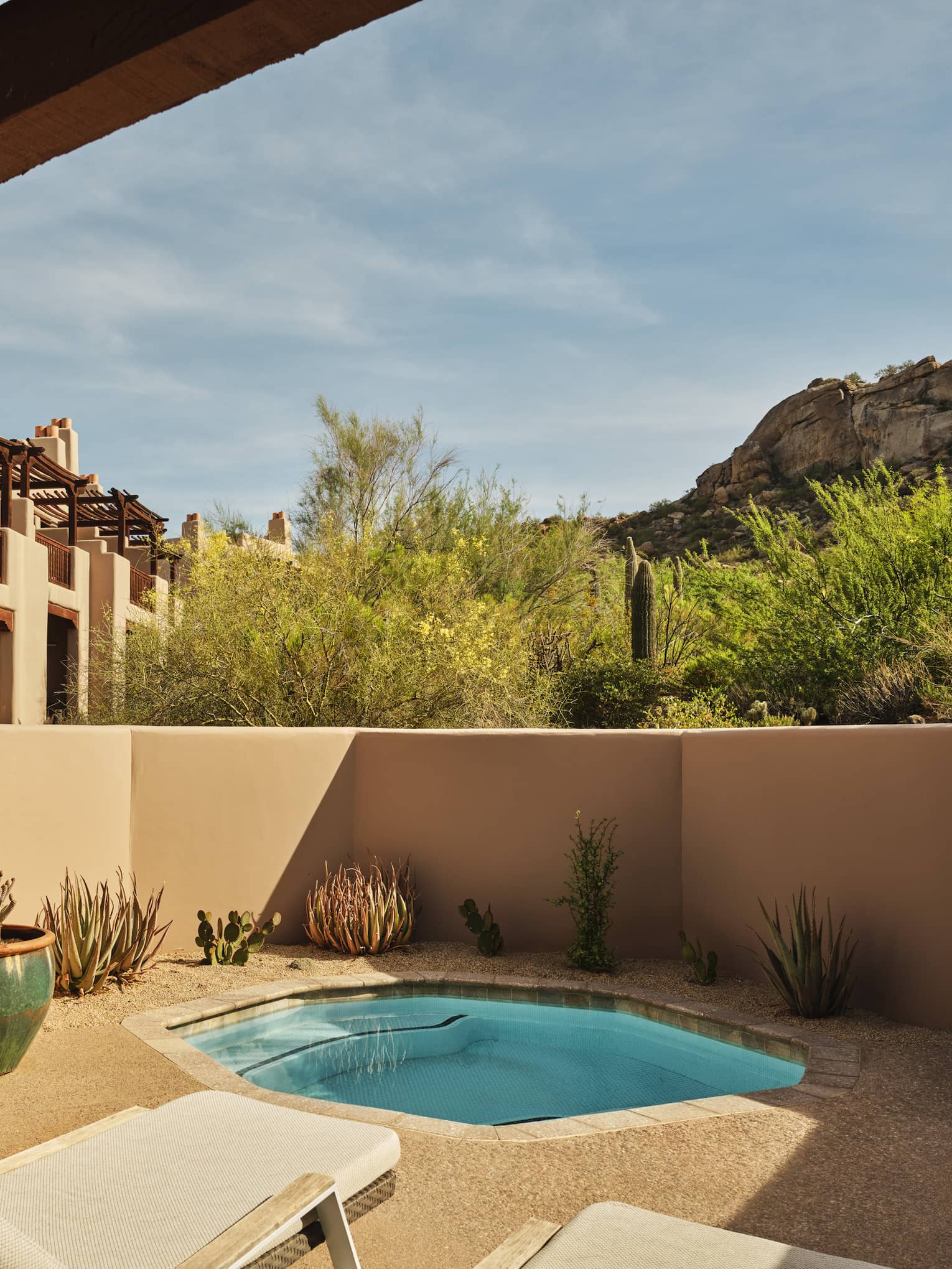 Plunge pool and two sun loungers on a walled-in terrace surrounded by desert landscape