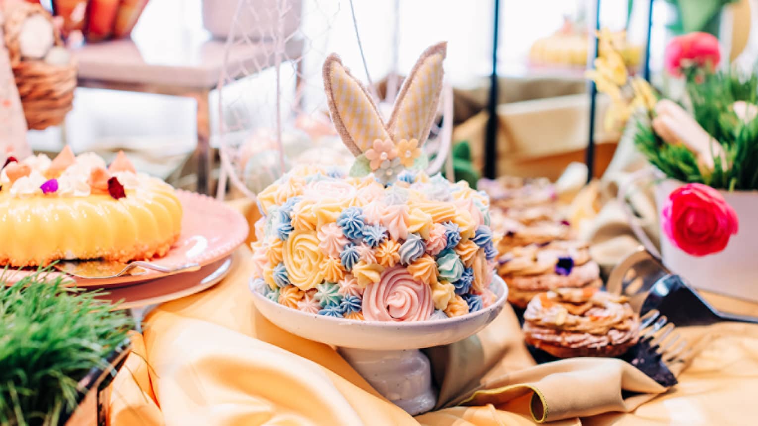 A cake with yellow, blue and pink icing and bouquets of flowers