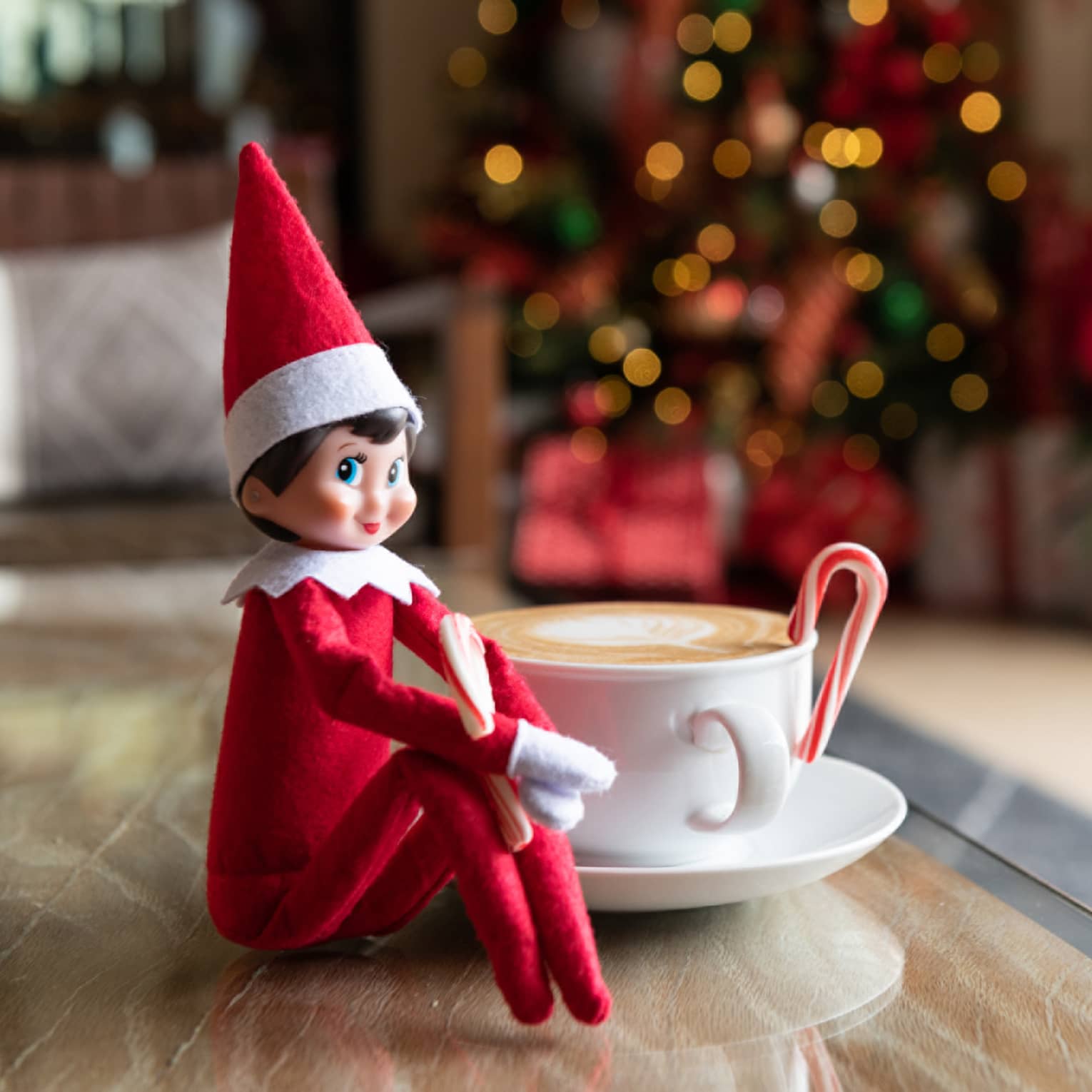 Elf on the Shelf sits next to a cappuccino