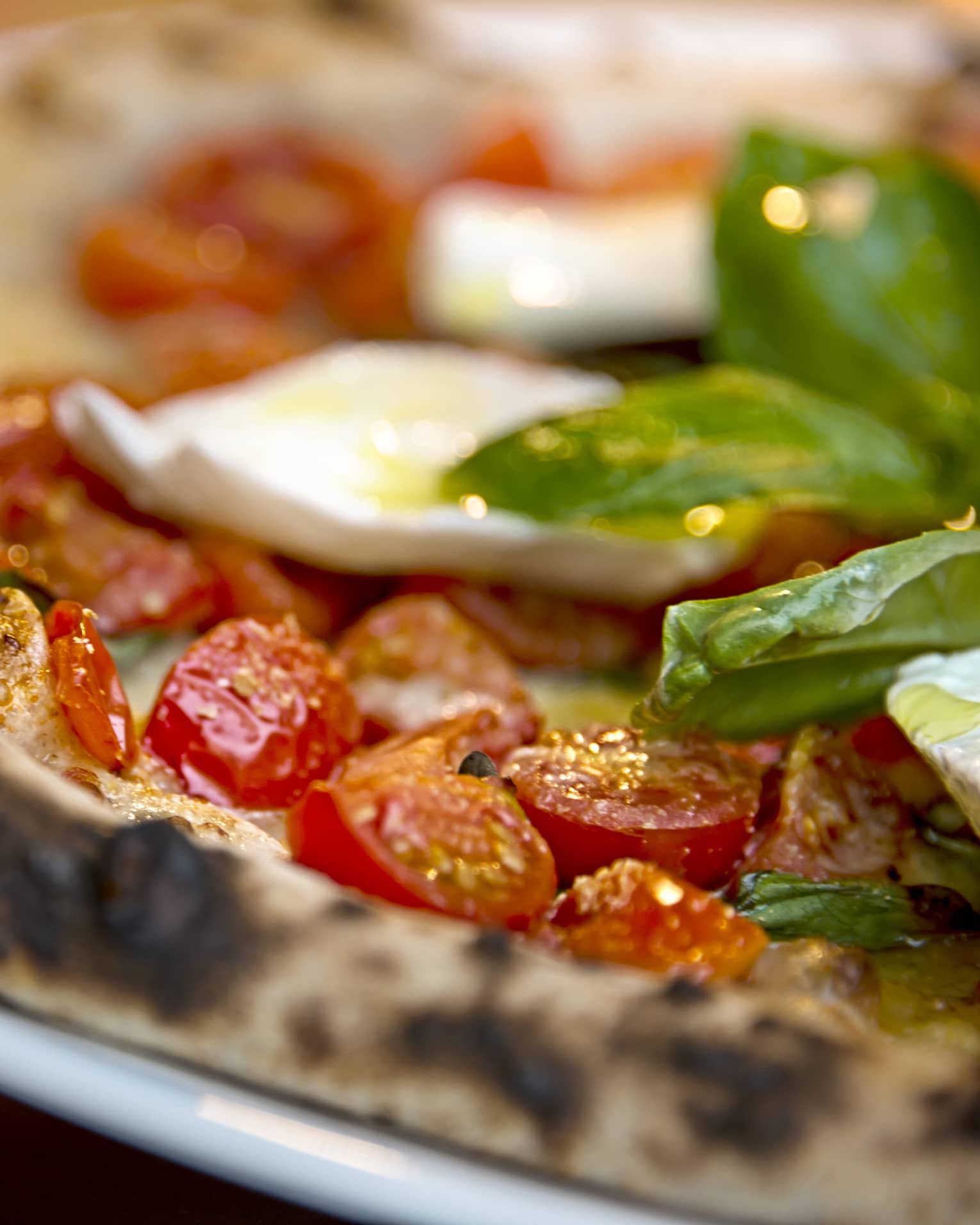Close-up of Al Fresco signature pizza thin wheat crust, fresh cherry tomatoes, basil