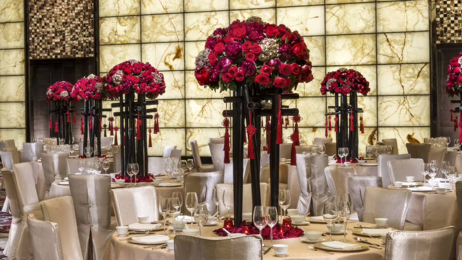 Grand Ballroom banquet tables and chairs with silk linens, red flowers in tall vases 