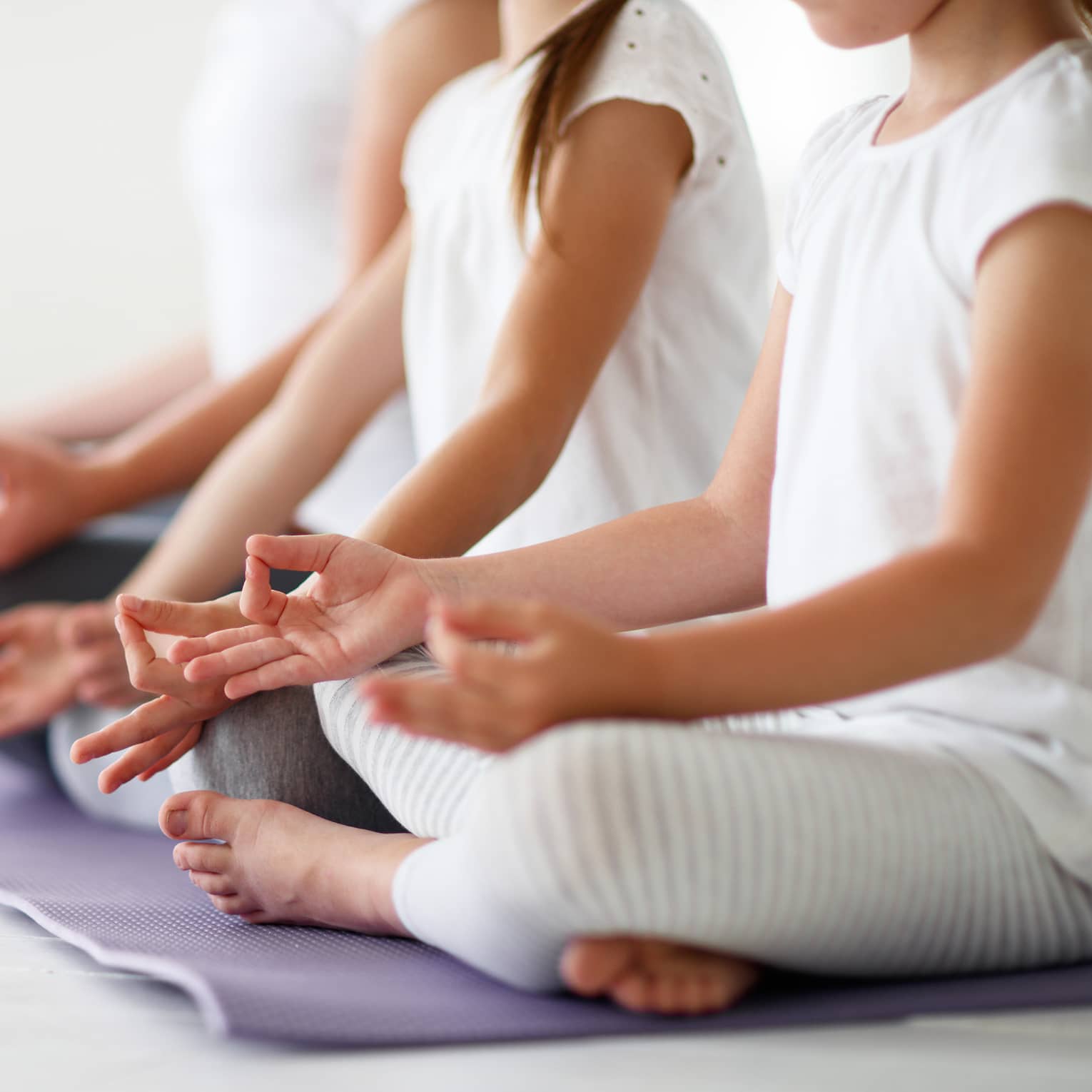 Young girls sit in cross-legged yoga pose