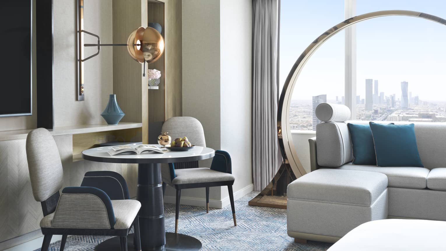 Window-side sitting area of hotel room, with small round table and two chairs