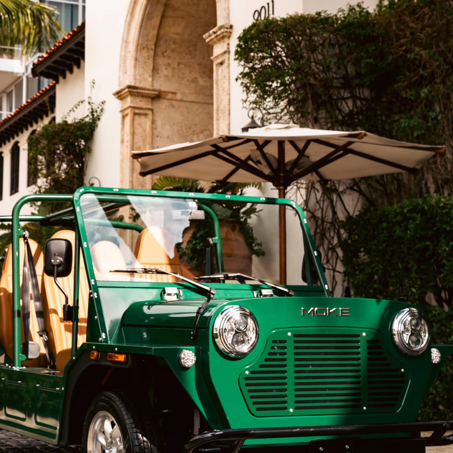 Green MOKE car parked outside of the building next to "The Surf Club" sign.