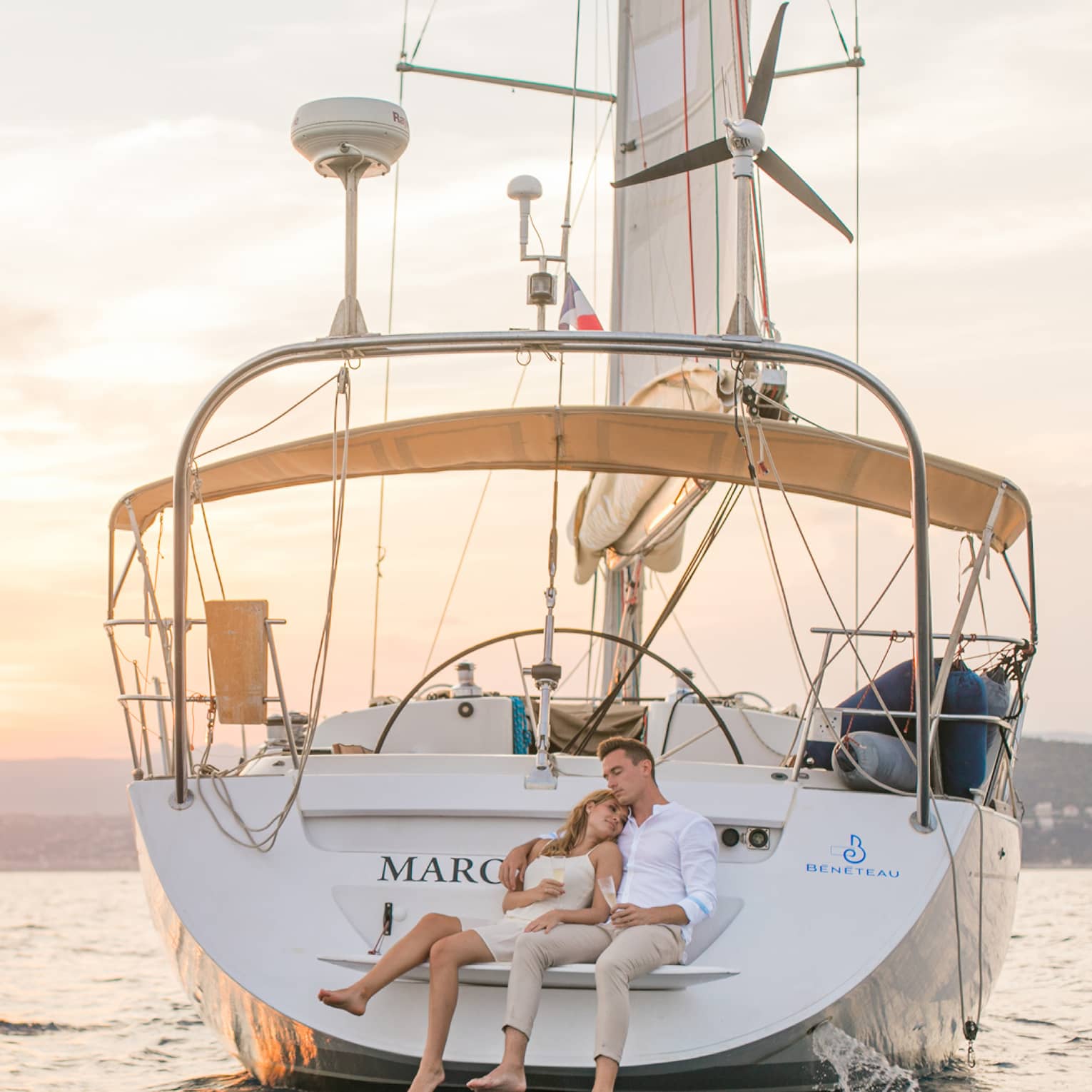 Couple leaning back on sailboat aft at sunset