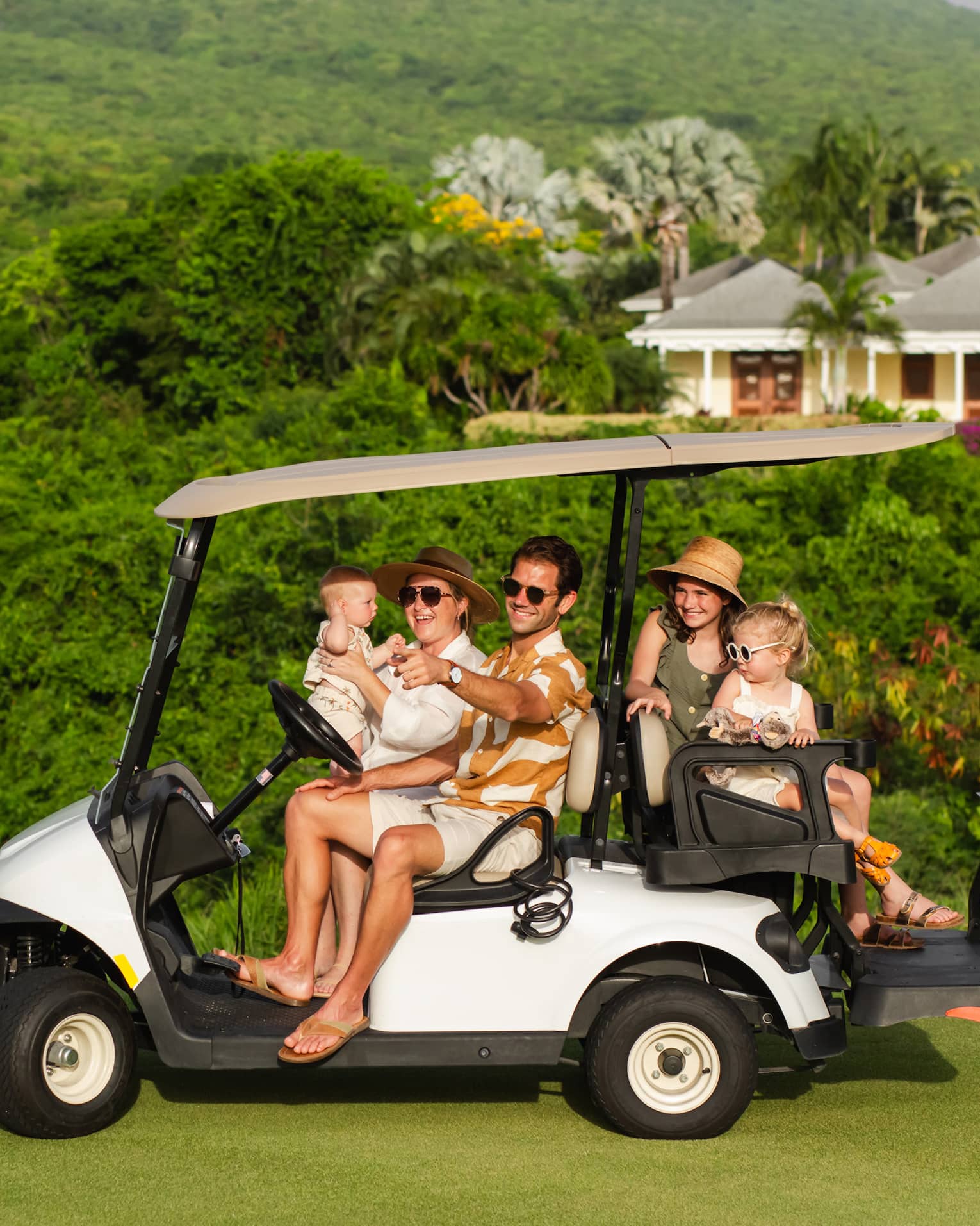 Five guests riding on a golf cart along a golf course