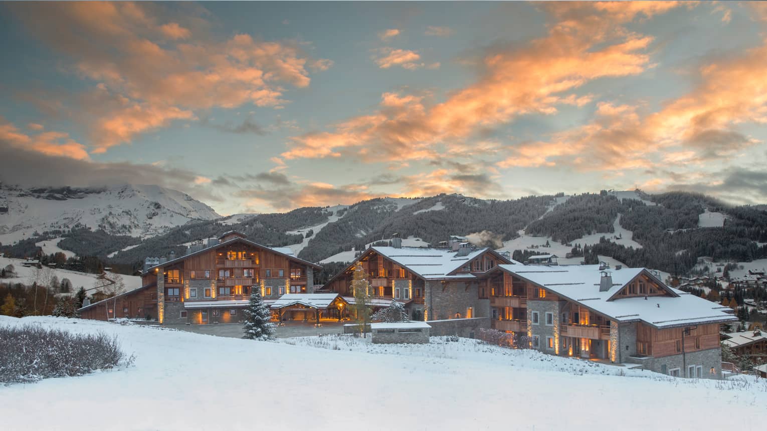 Four Seasons Hotel Megeve ski resort with lights at sunset on snowy mountain