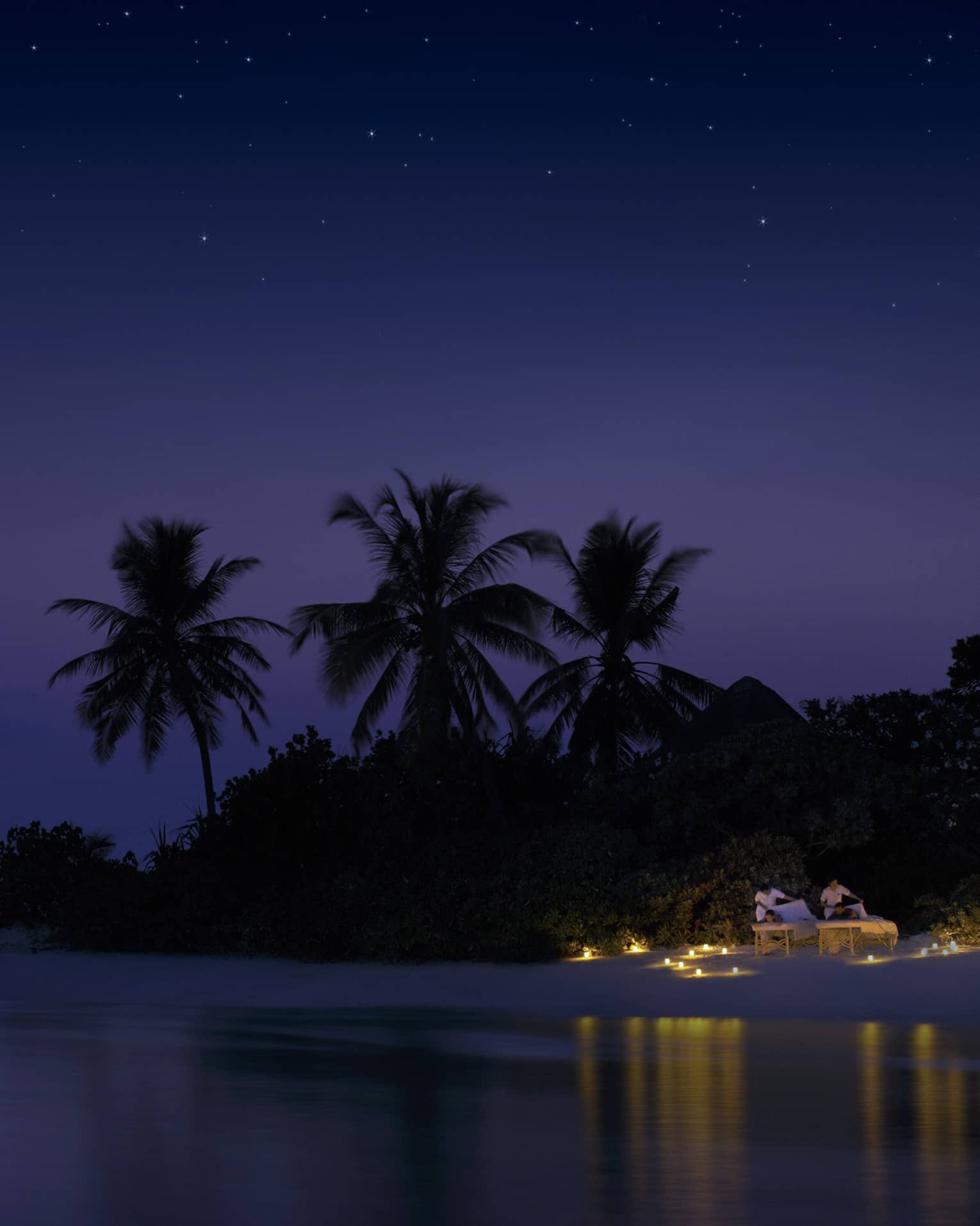 Night view of spa rituals, two guests have massages on candlelit beach under starry sky