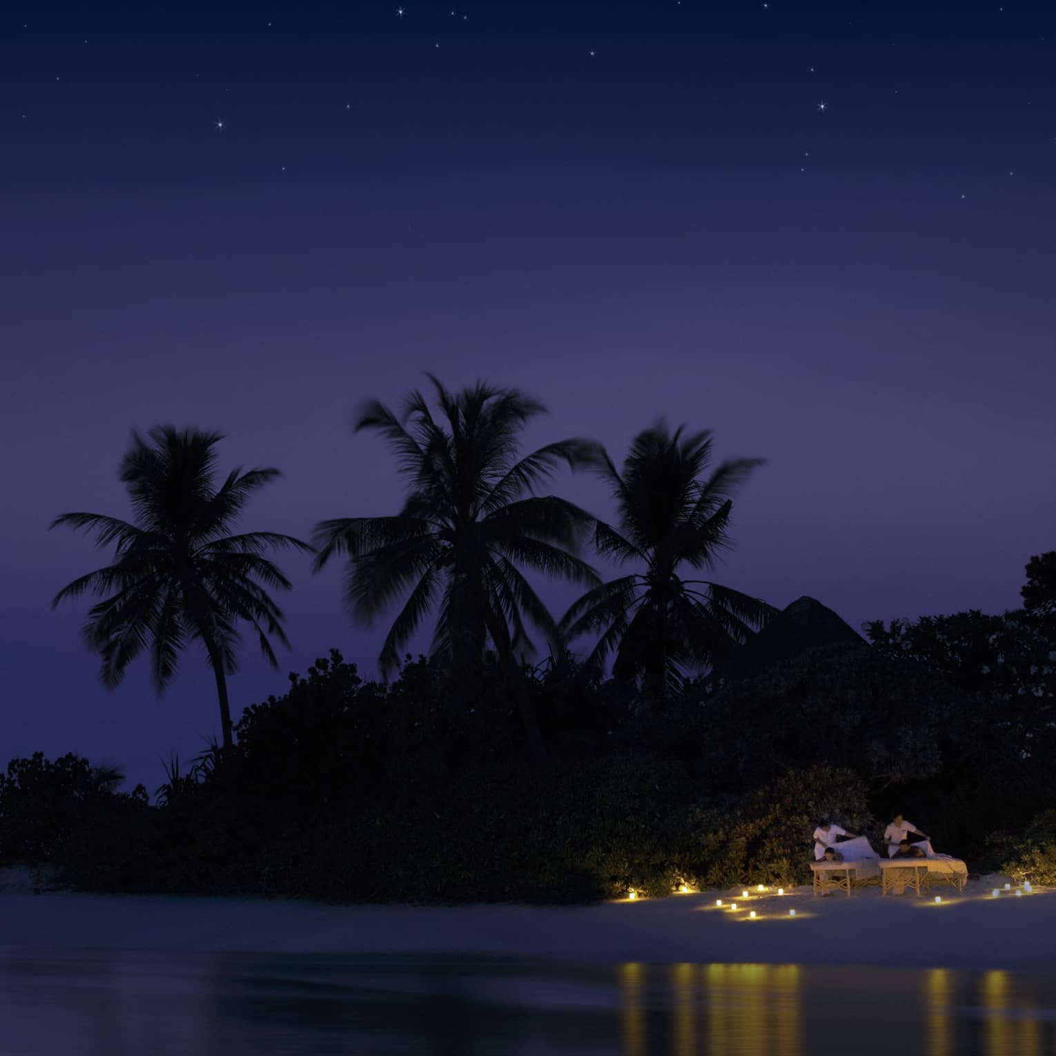 Night view of spa rituals, two guests have massages on candlelit beach under starry sky
