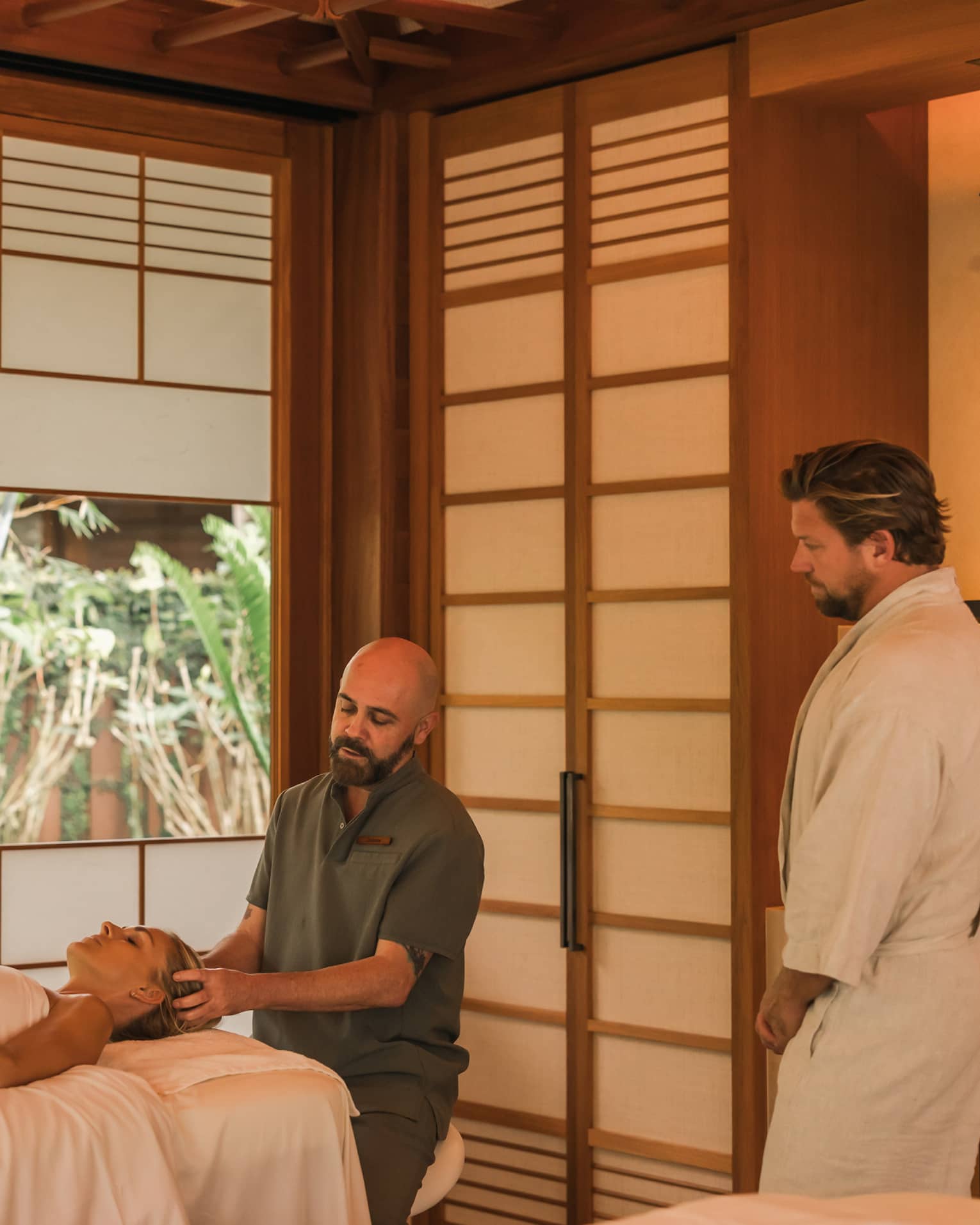 Man performs head massage on a woman laying on spa treatment table