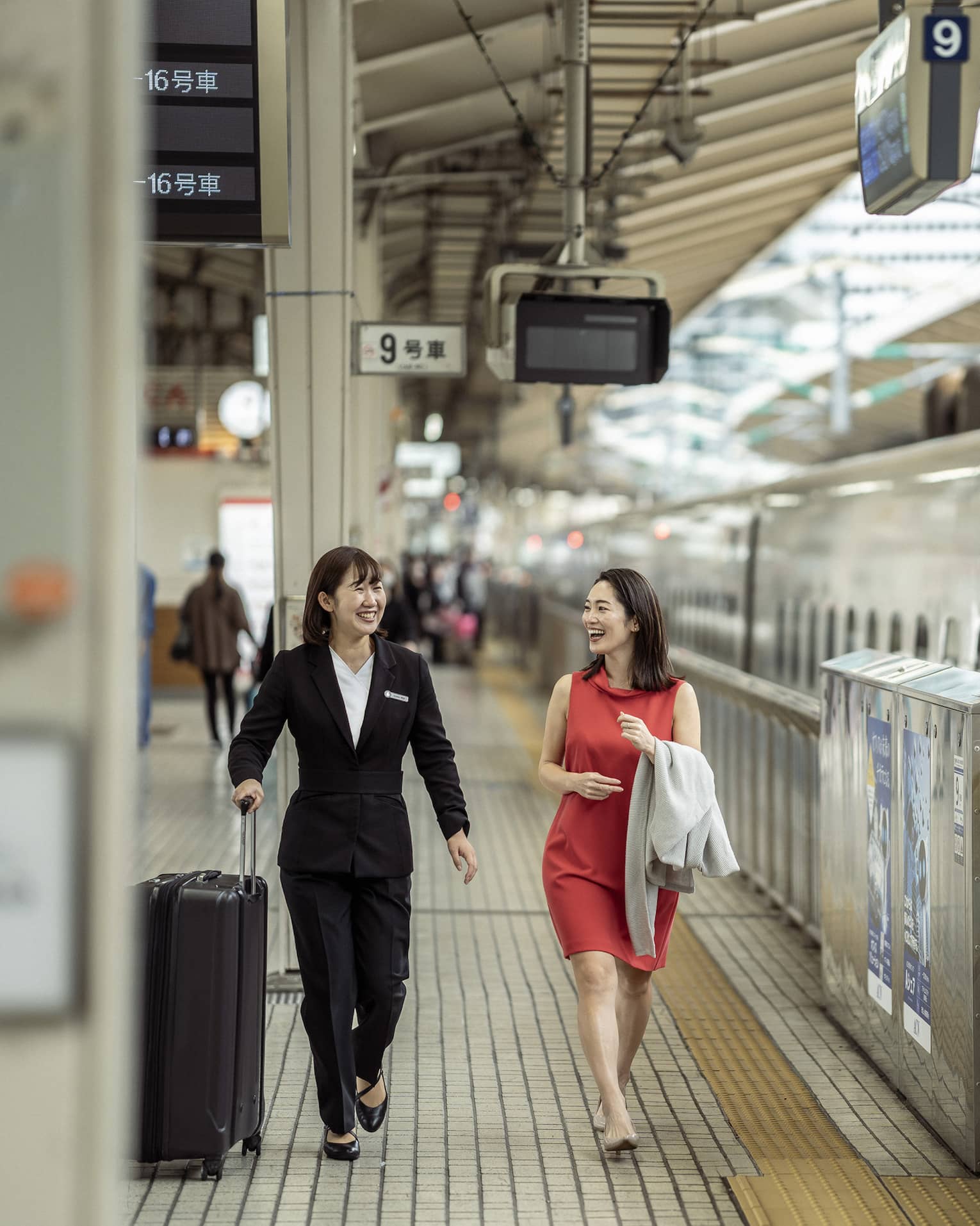 Train station greeter walks with female guest along the train platform