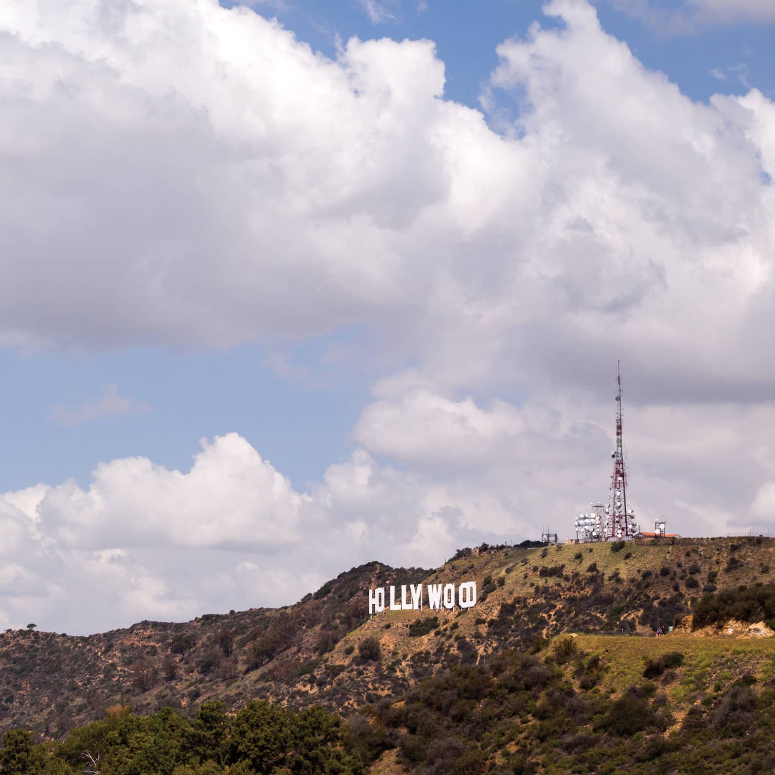 Hollywood sign on green Los Angeles hills against blue sky
