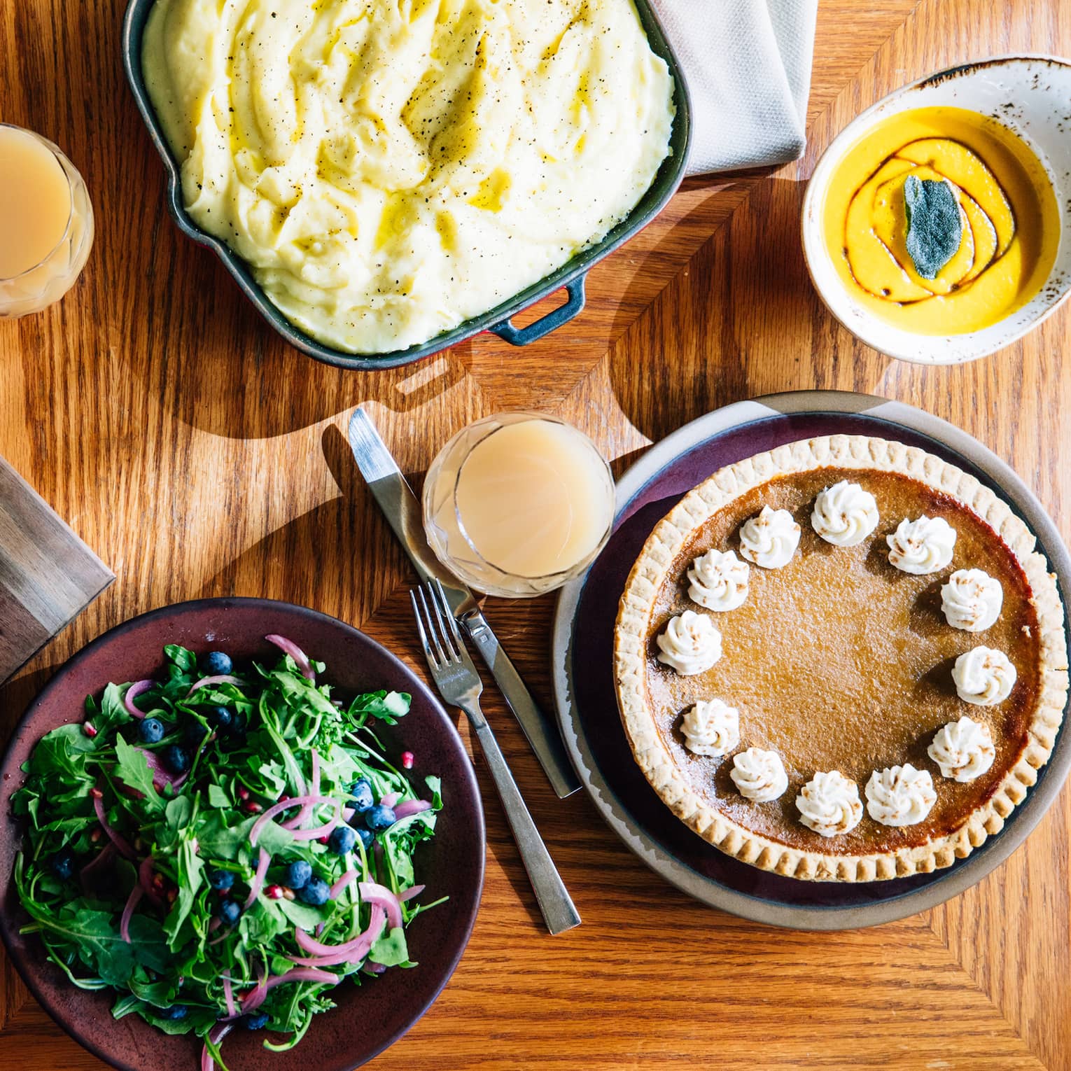 An aerial shot of a thanksgiving dinner including a roasted turkey with vegetables, mashed potatoes, salad and pumpkin pie