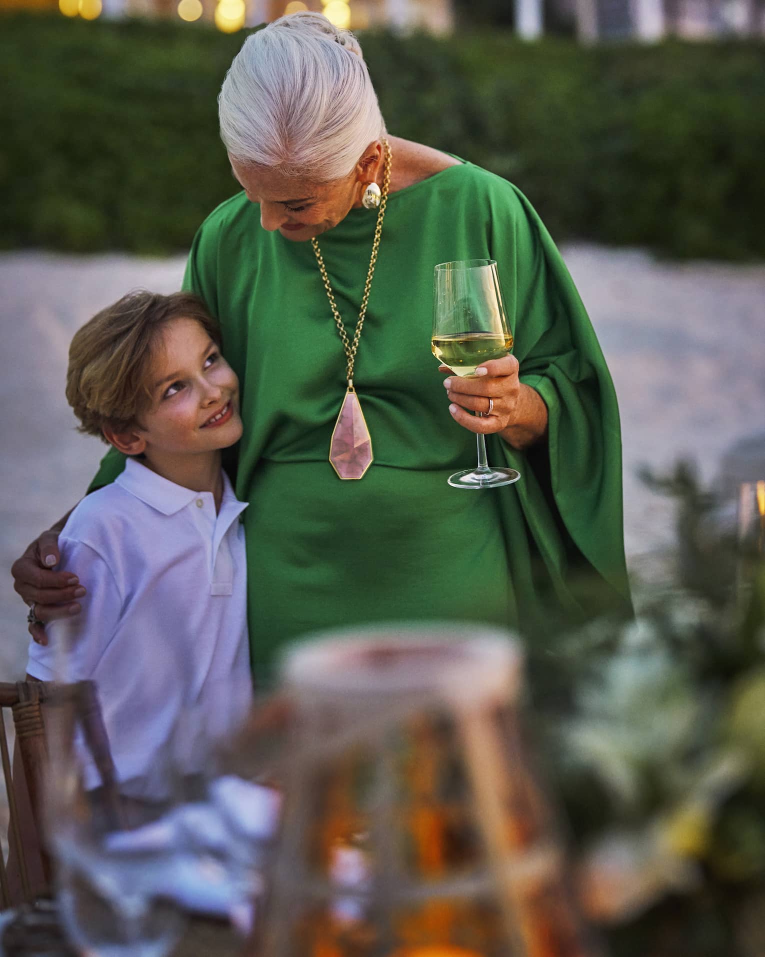 Grandmother and child hug next to a private dining table set on the beach