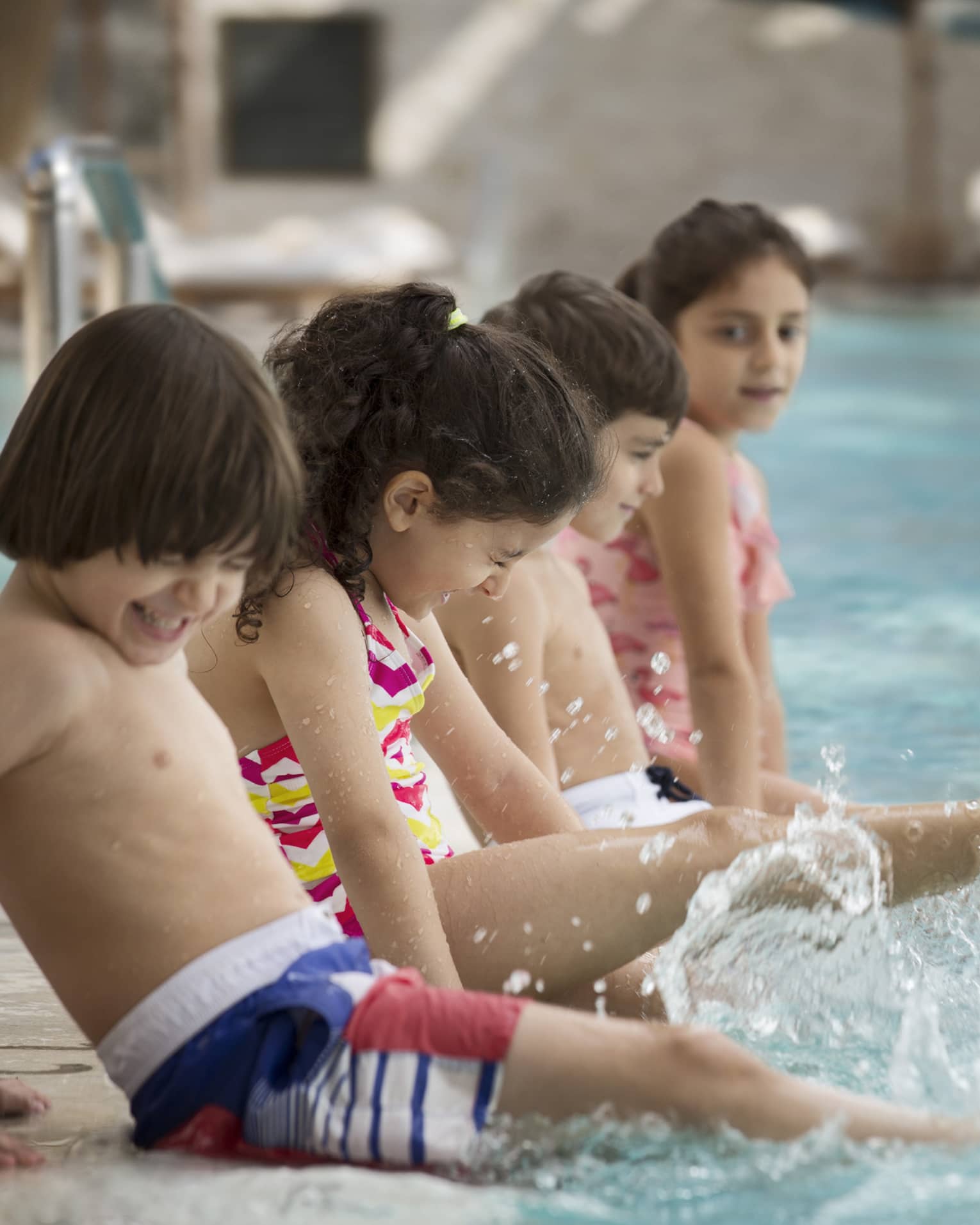Several children splashing at the pool.