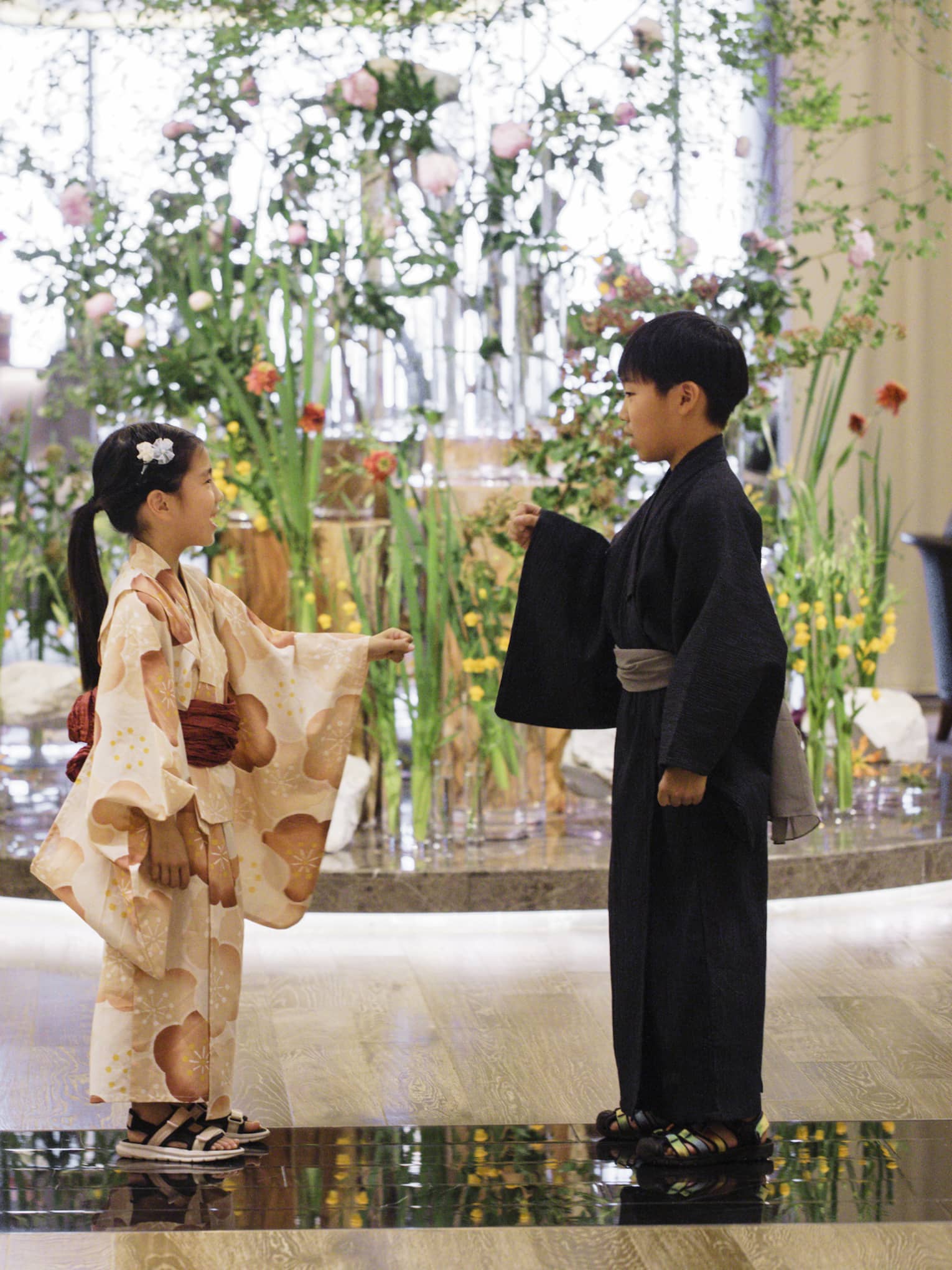 Two children dressed in yukatas stand in hotel lobby in front of elaborate floral floor display