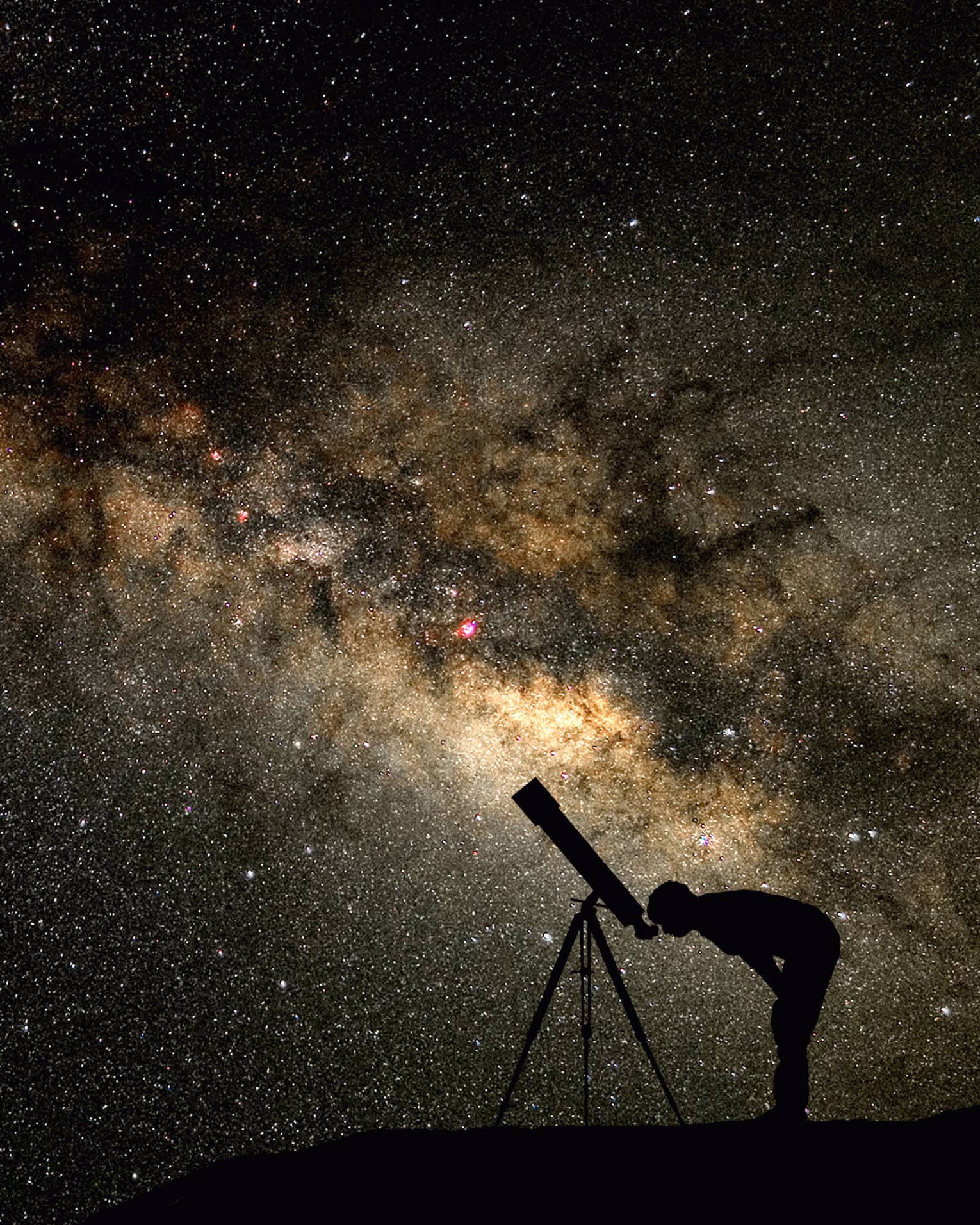 Silhouette of stargazer leaning into telescope against a starry sky, milky way