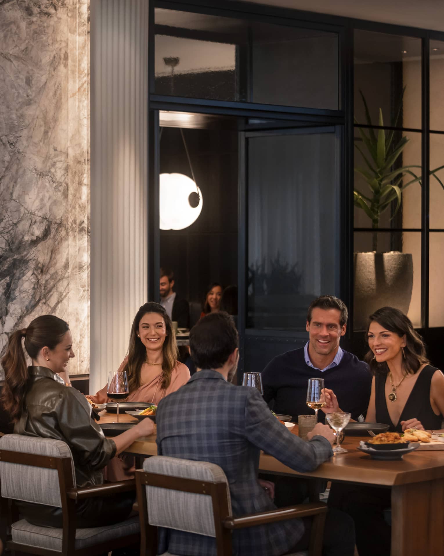 A group of people sitting at a large table in a dimly lit restuarant.