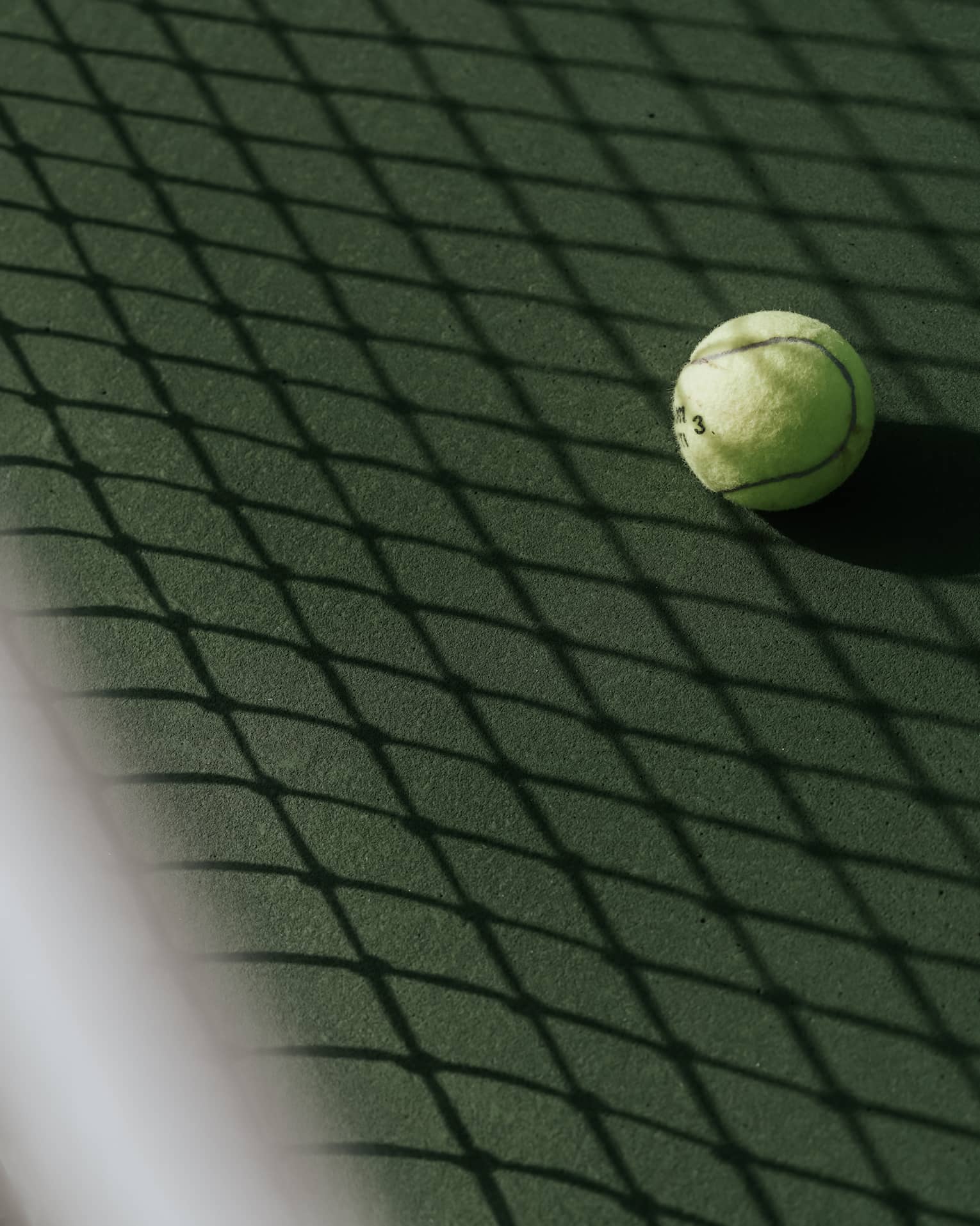 Tennis ball on tennis court with shadow of net