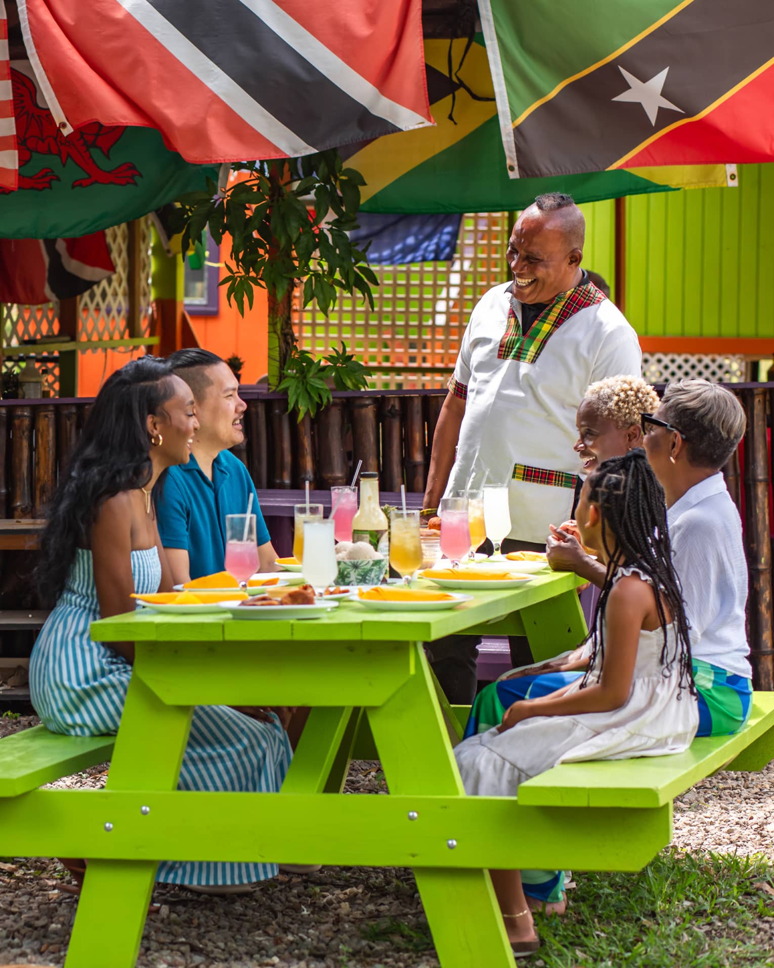 Guests sitting at a picnic table outside under a large tree