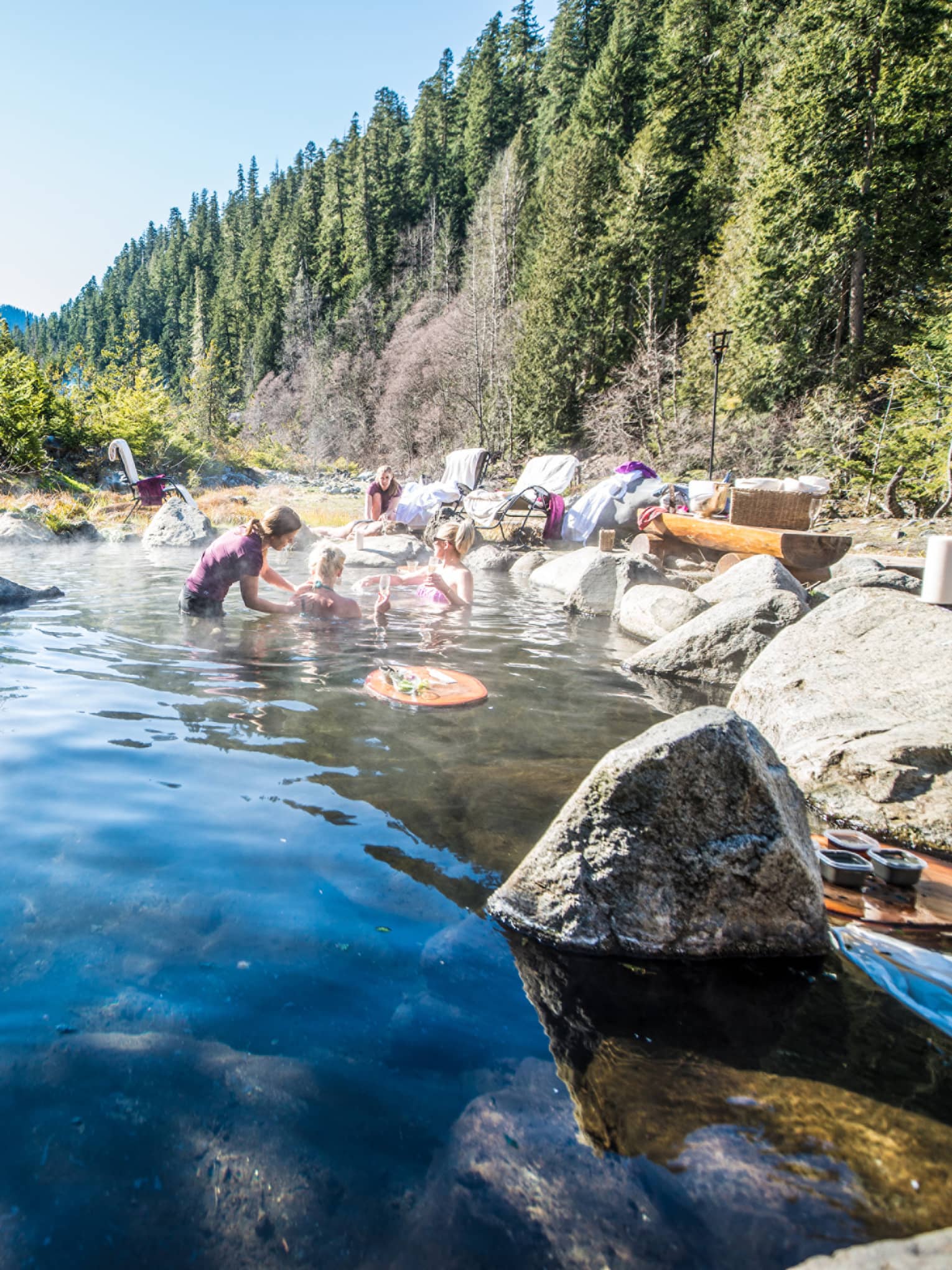 Group relaxes in hot springs, surrounded by forest